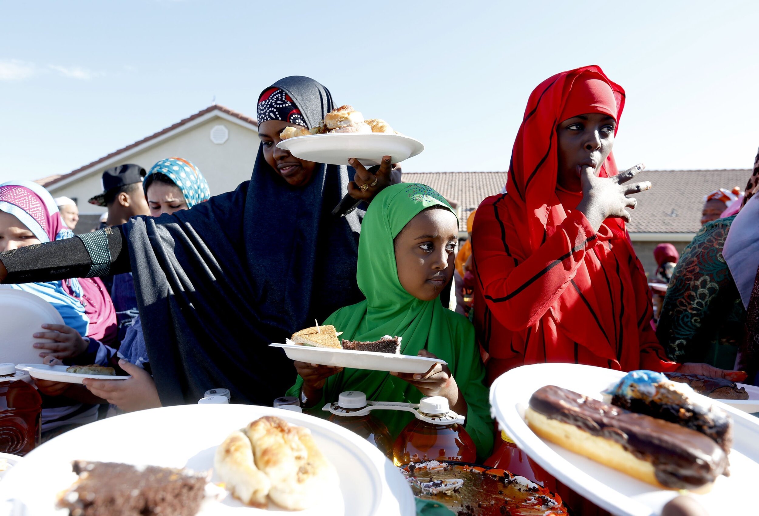  Fozia Yussuf, 10 of Pasco, center, looks on as her cousin Fahima Ise, 15 of Pasco, licks her finger while getting food Friday to celebrate Eid al-Fitr at the Islamic Center of the Tri-Cities in West Richland. Over 500 people gathered to celebrate th