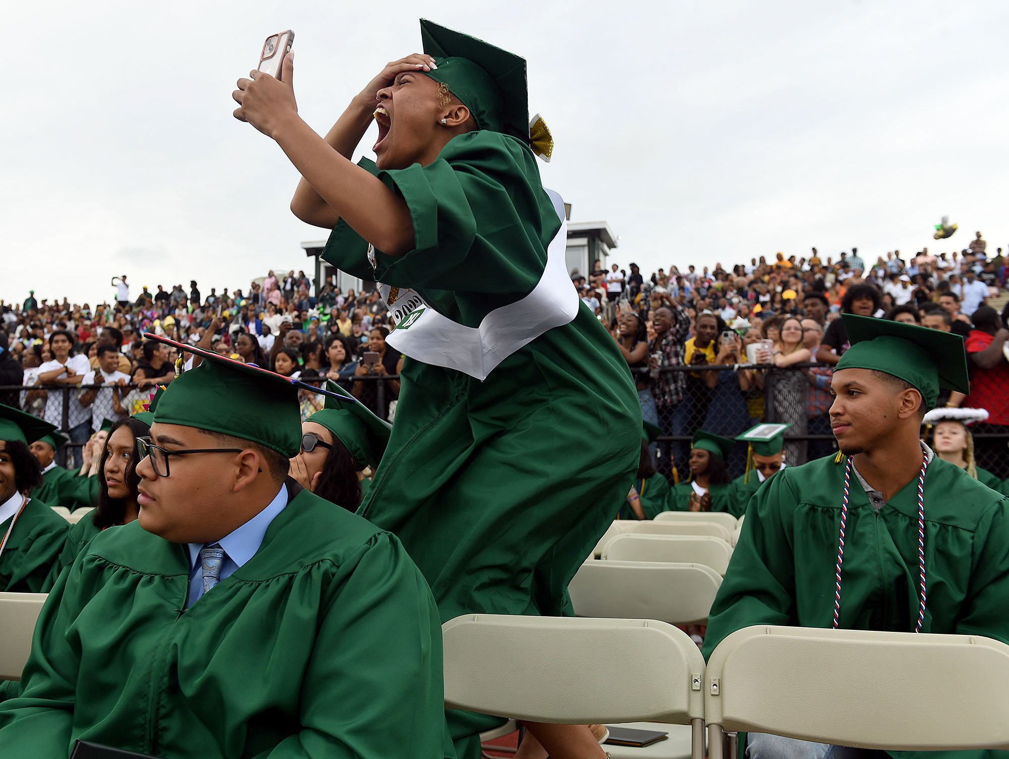  Graduate Joi Garrett jumps and screams as she takes a video of a friend receiving their diploma during a commencement ceremony for New London High School Tuesday June 21, 2022. (Sarah Gordon/The Day)  