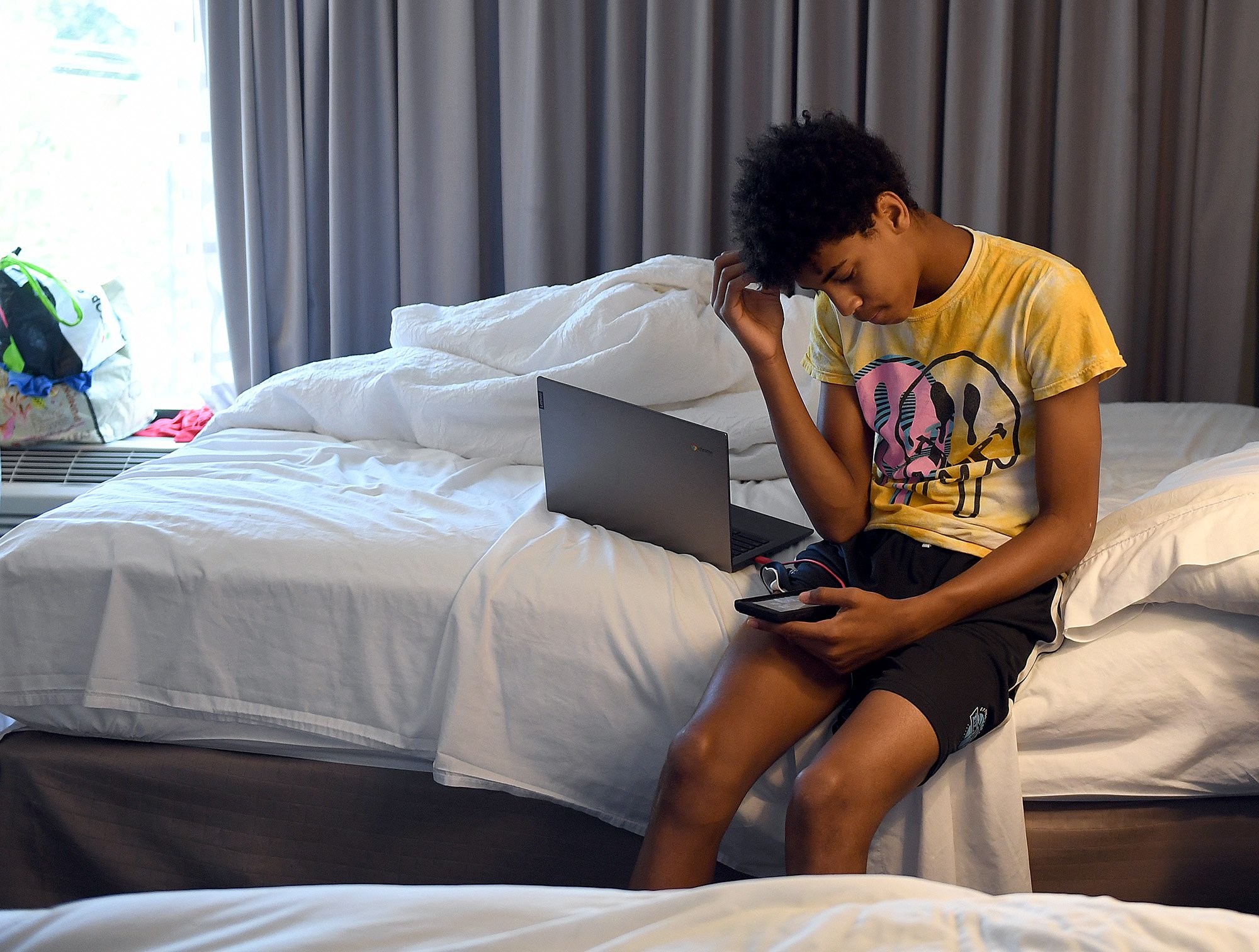  Malkhi Sabb, 14, sits on his mother’s bed as he looks through his phone at the Hampton Inn in Groton Wednesday, July 13, 2022. Christina Tejeda  and her three sons are staying at the hotel while their apartment in Branford Manor is being cleaned of 