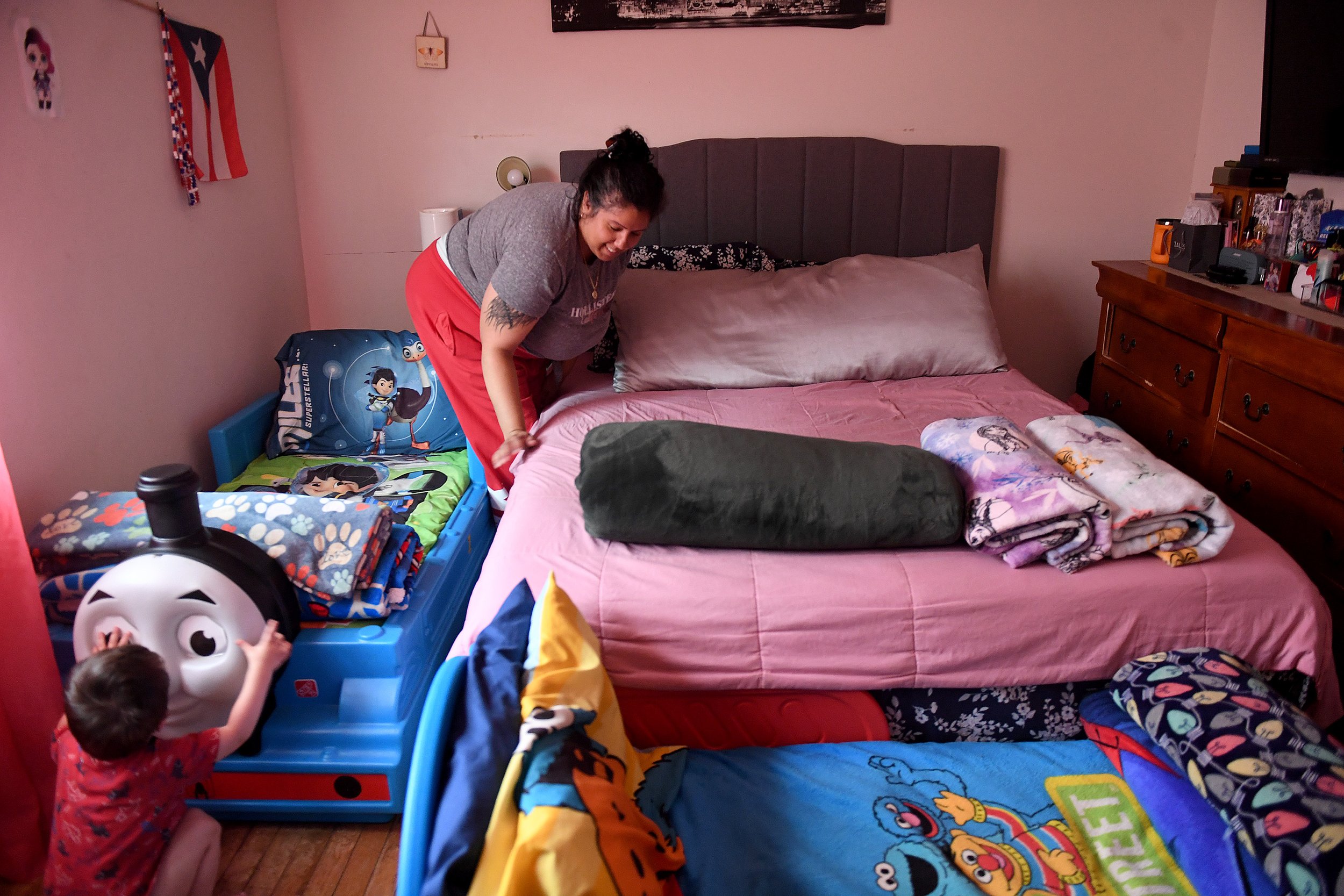  Christine Santos makes the bed as her sons play at their Branford Manor home in Groton Friday, June 17, 2022. Santos shares the bedroom with her two sons, climbing over their twin beds to get into hers, so her teenage daughter can have her own room.