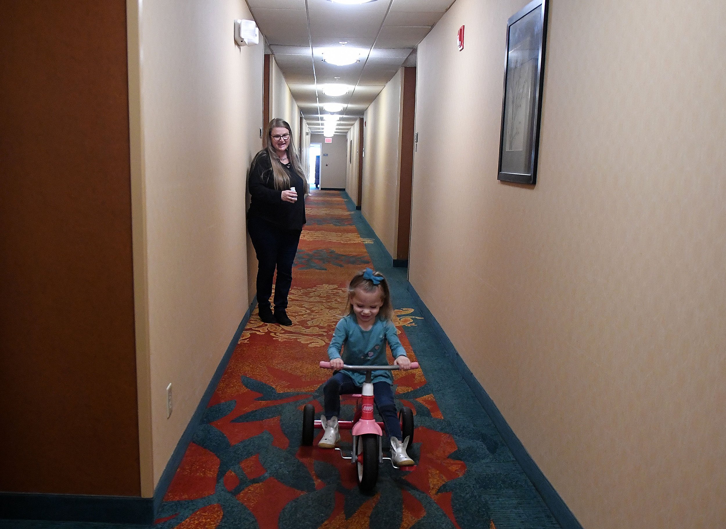  Azrielle Levy, 2, rides her trike down as her mother Valarie watches the hallway of the Residence Inn Mystic on Wednesday, November 2, 2022. With no playground they can walk to Valarie struggles to keep the active toddler entertained in a hotel room