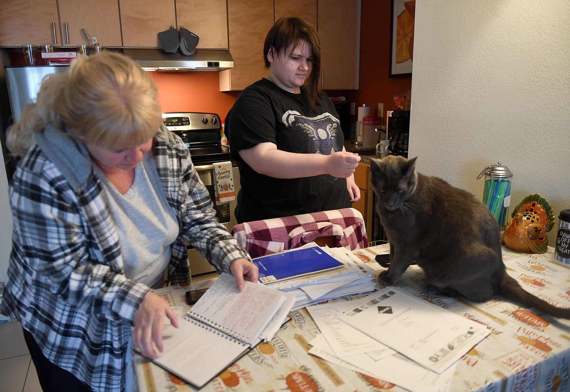  Sandra Fetters looks through her notes as her daughter plays with their cat Earl at the Residence Inn Mystic in Groton Monday, October 31, 2022. Sandra, her two daughters and three cats have been at the hotel since leaving their apartment at Branfor