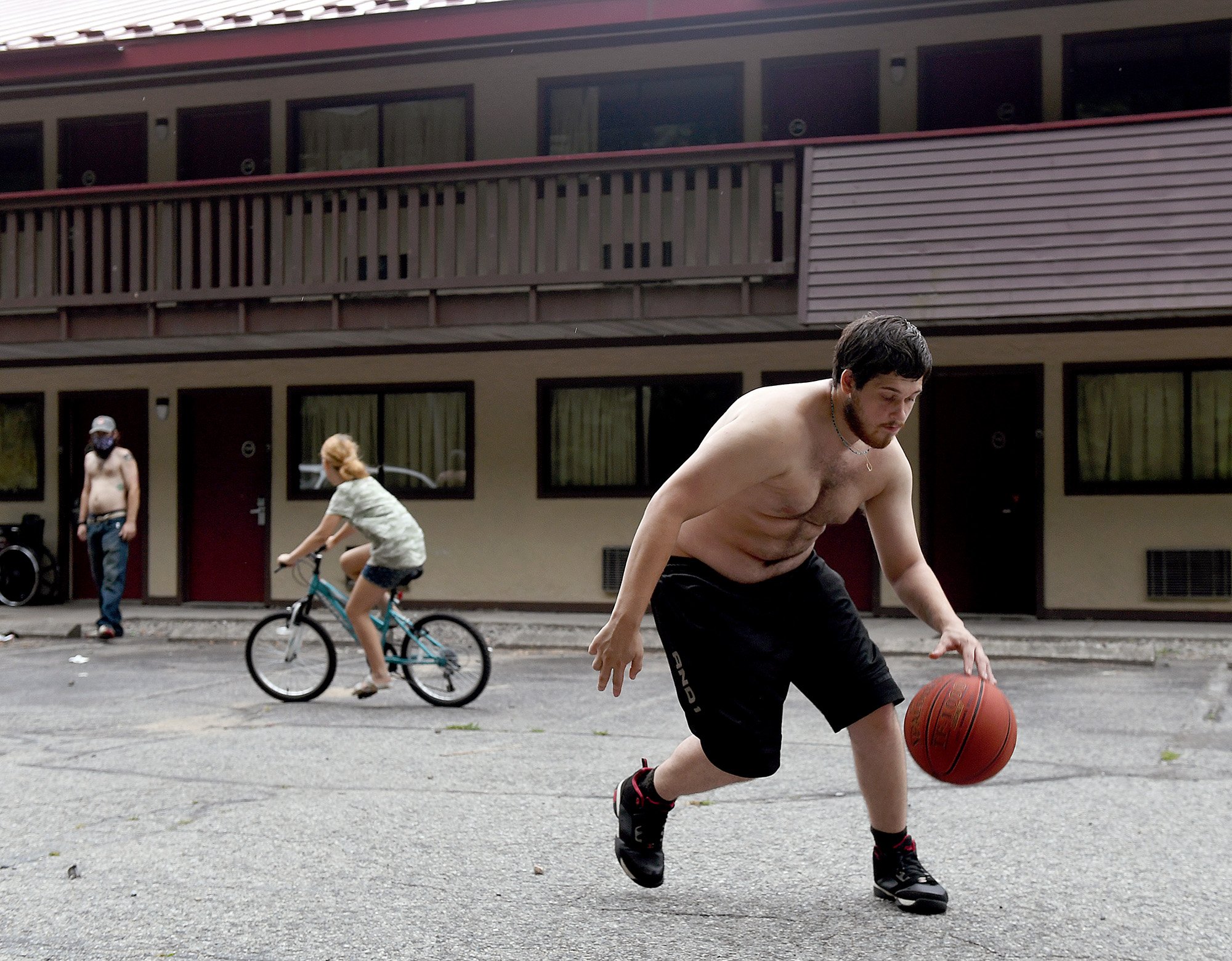  Mike Roy, 18, dribbles a basketball in the parking lot outside his family’s room at the Red Roof Inn in New London on Monday, August 8, 2022. Roy has lived at the motel with his mother Sabrina Babey and her fiancé William Waddicor two dogs and a cat