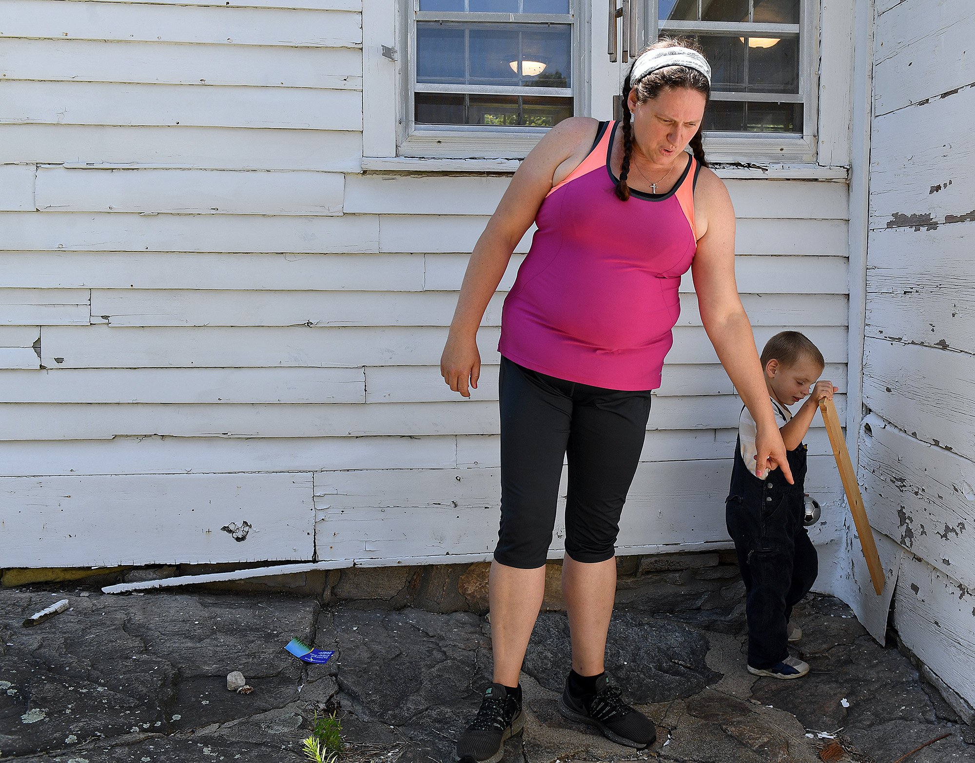  Rebecca Linder points out lead paint chips falling from the exterior of her home in Ledyard as her son Mark Nathan, 3, plays Monday, July 11, 2022.  Linder is the caretaker of Nathan Lester House where they live and all of her children have had elev