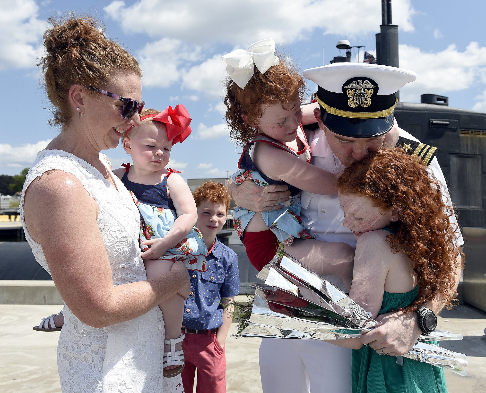  Lt. Cmdr. Steven Halle, Executive Officer, hugs his daughter Erin, 10, while holding Margaret, 5, as his wife Alissa, from left, Maeve, 18 months, and Rowan, 8, look on during the homecoming for the USS Hartford (SSN 768) for its return to the Naval