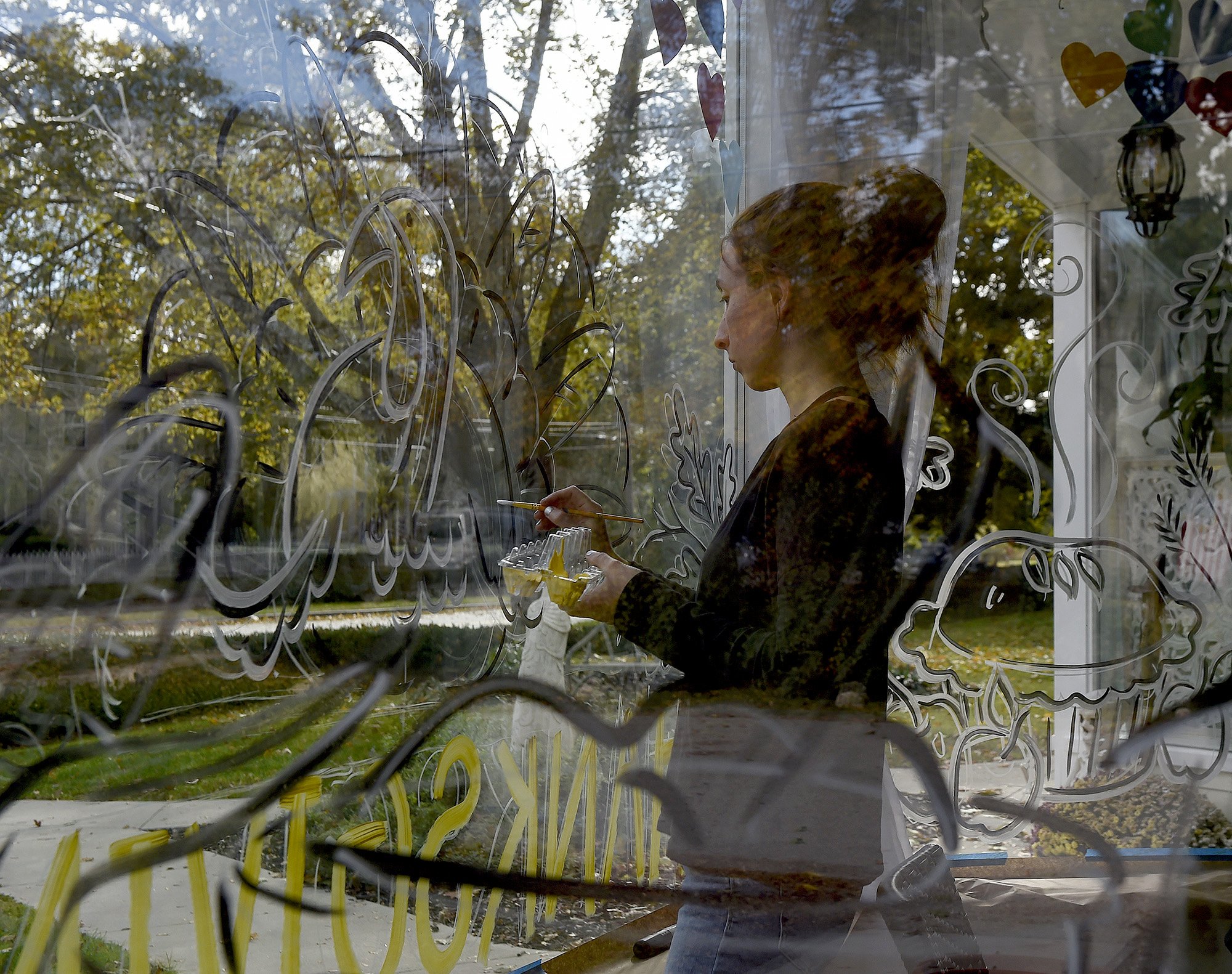  Gloria Creamer works on painting the windows of The Chocolate Shell in Old Lyme for Thanksgiving on Monday, November 2, 2020.  Creamer, who also paints the windows of a few other stores on Lyme Street, said she works with owner Barbara Crowley, to r