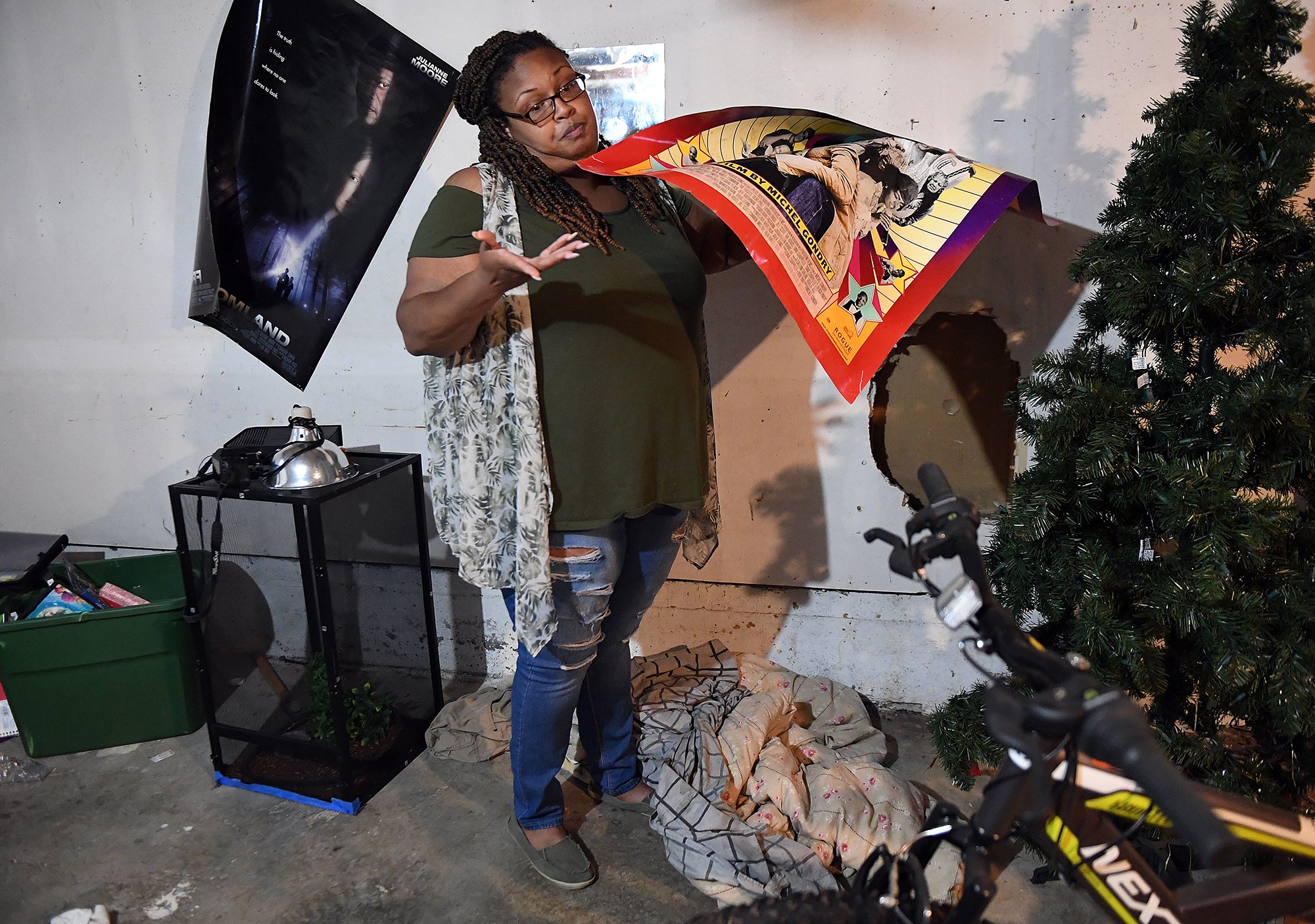  Latasha Burage moves a poster covering a hole in the drywall that has been in the basement of her Branford Manor apartment in Groton since she moved in Wednesday, September 1, 2021. (Sarah Gordon / The Day)  