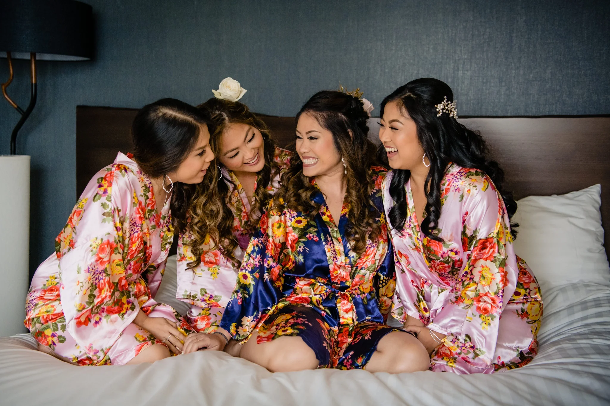 bride and her bridesmaid on the bed laughing