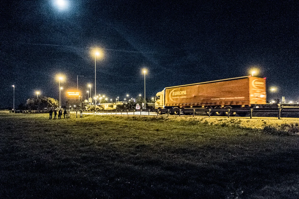 Waiting by the highway for the right moment to cross so that the police won´t see them.