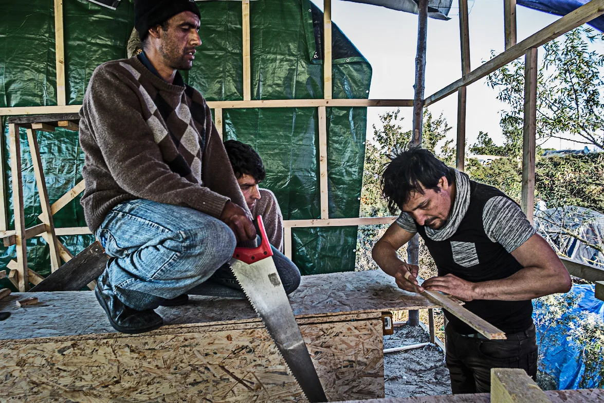 Afghan men building a restaurant. Some of these men gave up trying to go anywhere and decided to built their own businesses around the camp. Do with what you have.