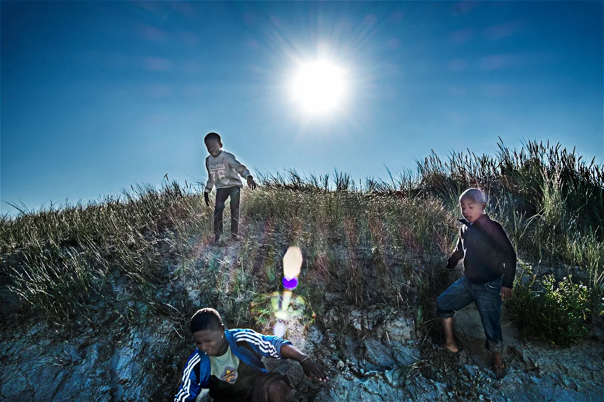 Children playing on the beach located behind the camp. "Here´s England" they say as they point their finger towards the sea. Children and women are kept inside the jules ferry center which is supervised by the organisation " La vie active". It is a special day when they get to go out and play on the beach.