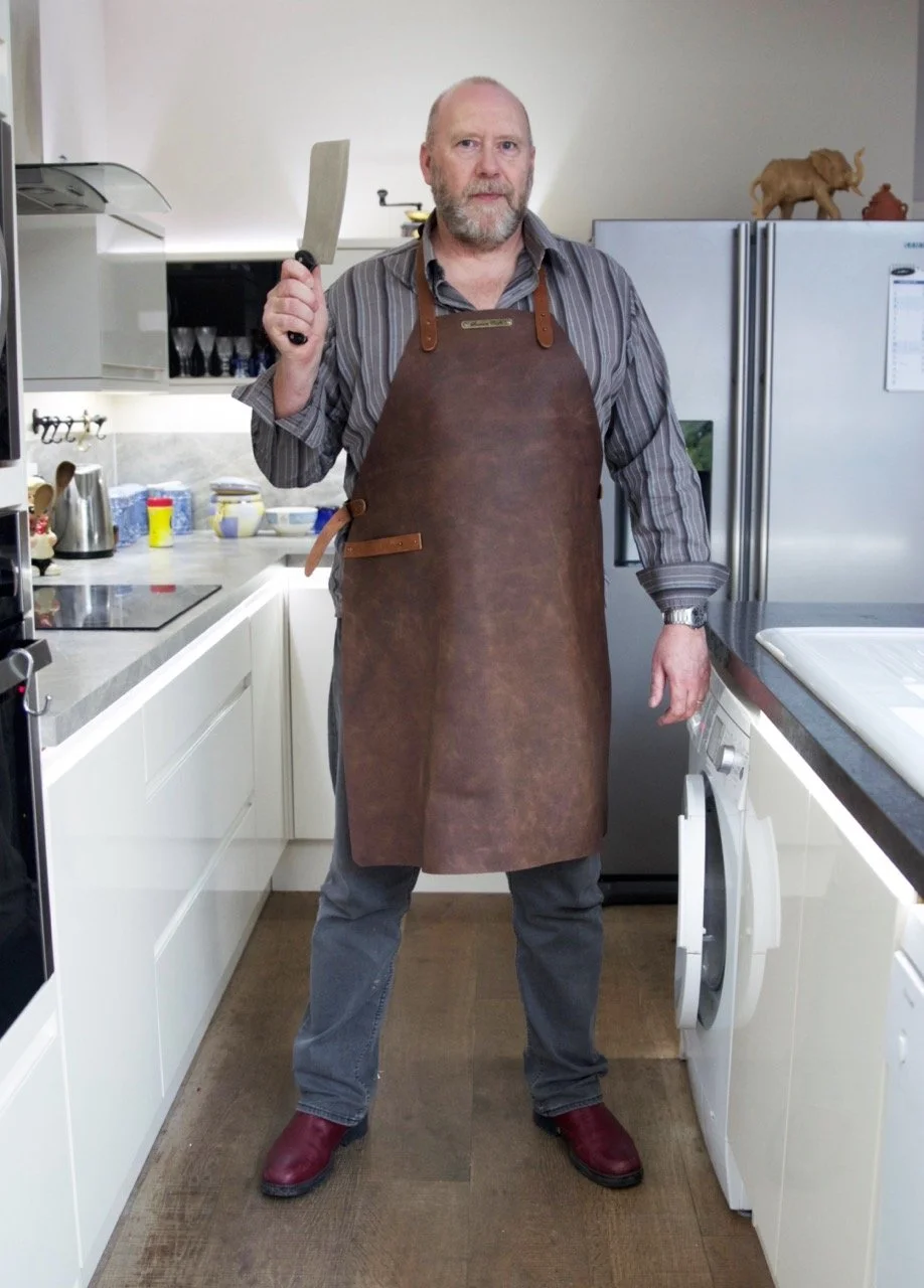 A man holding a cleaver wearing a Stalwart Craft Classic Leather Apron