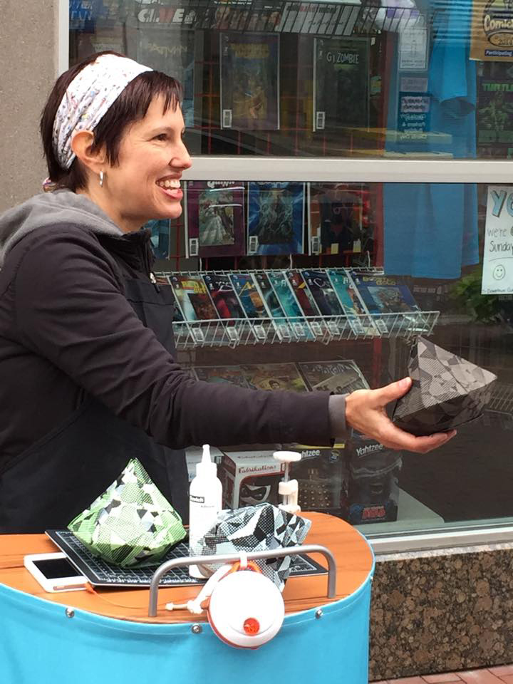 I cut, folded, and glued gems and gave them away. Everytime I interacted with the public--giving away these handcrafted gems and stickers--I played an 8-bit "level up" sound through the small speaker pictured at the front of my portable work station.