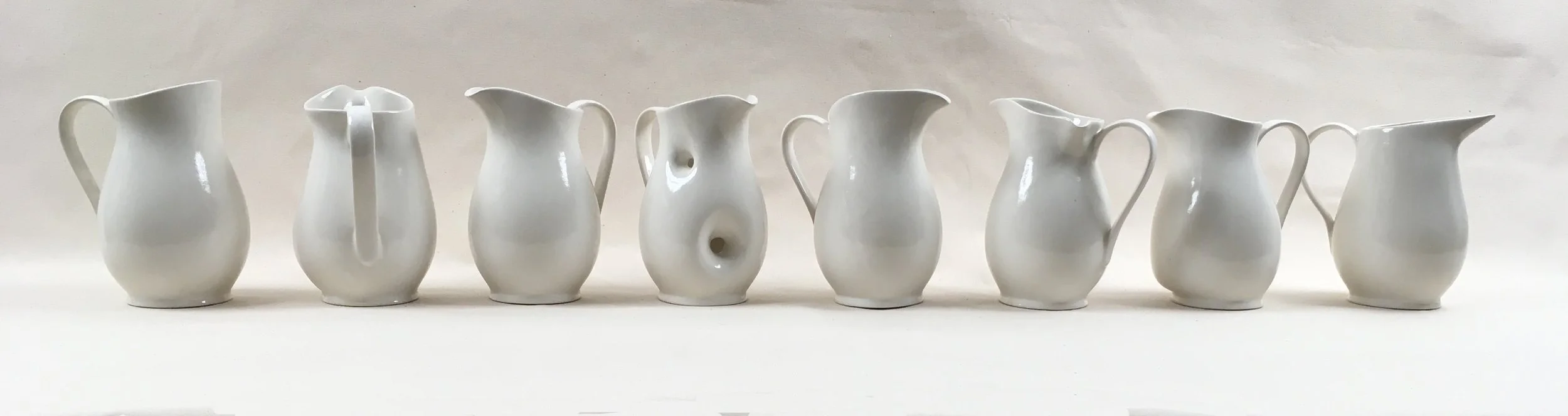   Variants , 1995, stoneware, approx. 12x80x12”  Eight stoneware pitchers were cast from a mold and uniquely modified.   