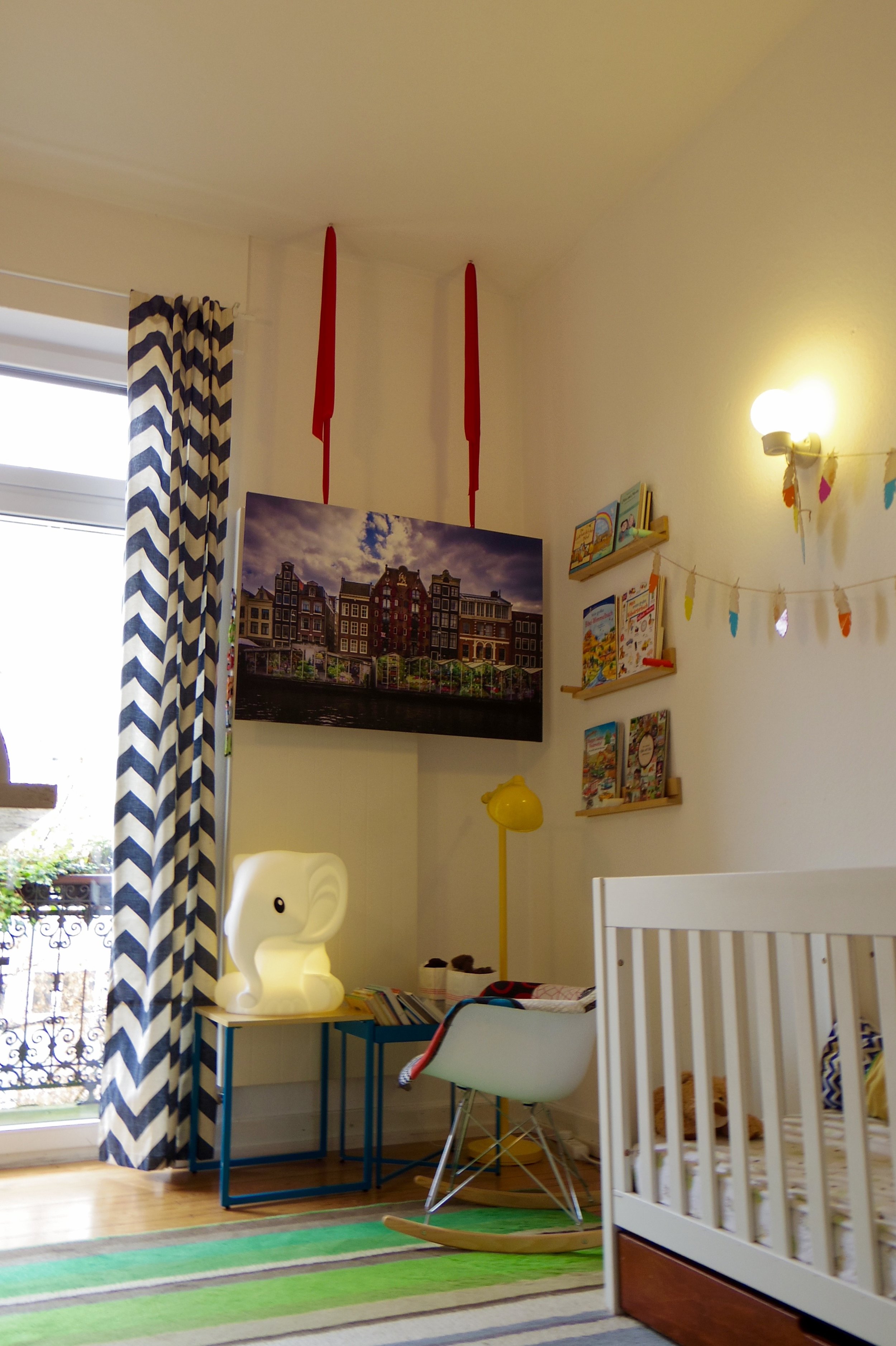 Unable to hang art on the reading corner wall due to the tall wall radiator, the canvas is hung from the ceiling with playful ribbons, reminiscent of a maypole. 