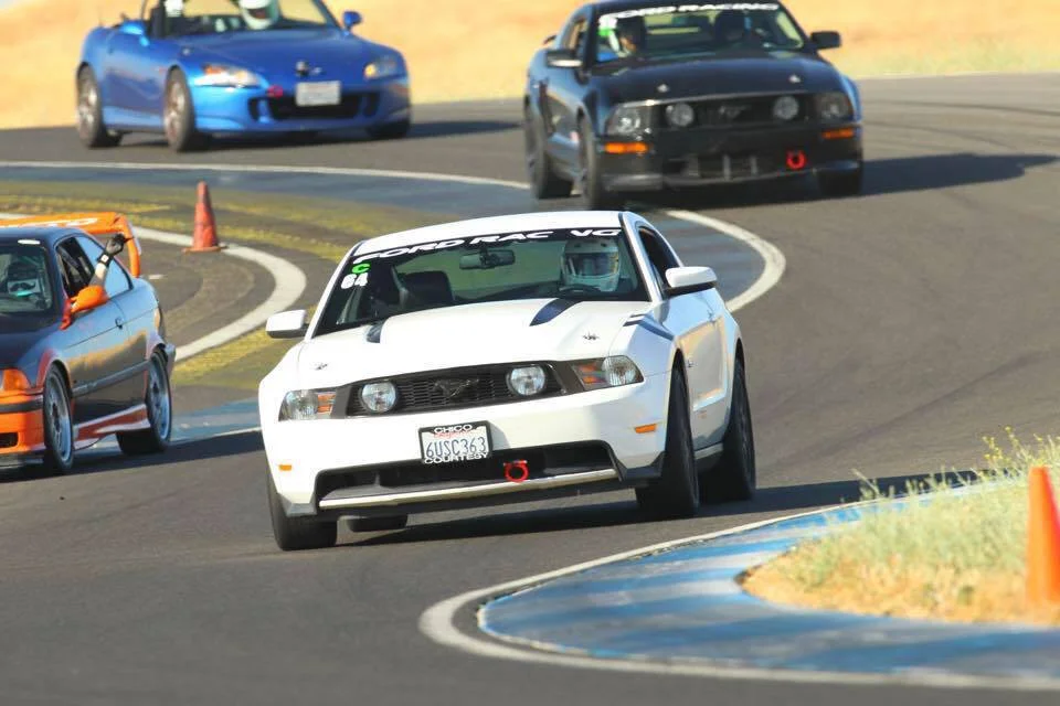 Dan being chased down in his white Mustang by his son Gerrit in his black Mustang at Thunderhill Raceway.