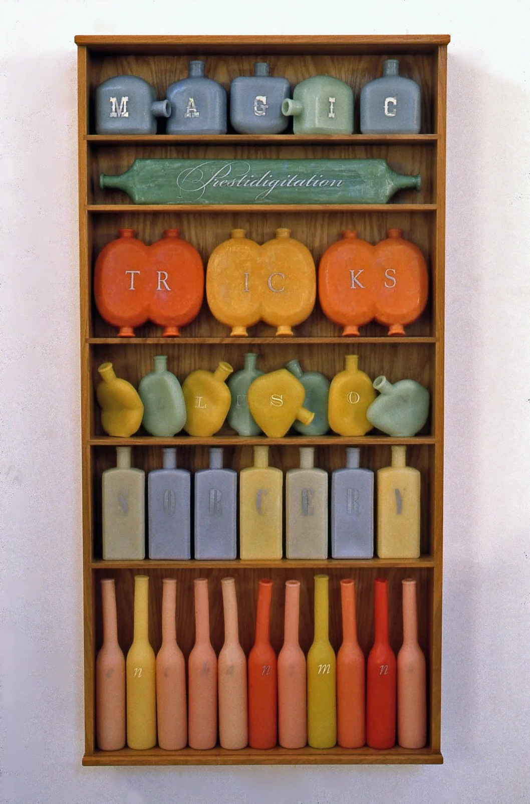  Names of Magic, 2000: wax, wood, metal leaf, 54 x 27 x 5 1/2 inches. Each row of bottles spells one word.
Top to bottom: Magic, Prestidigitation, Tricks, Illusion, Sorcery, Enchantment. (On the reverse of Tricks, it reads Treats.)

