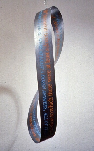 Noir moebius, 1991-4: Galvanized steel moebius strip, text silkscreened in two directions along edges, chain.
Meanwhile, back at the ranch, she turned to me and asked, “what’s someone like you doing in a story like this?” I handed her my card. About a thousand years passed, as her eyebrows worked themselves into a question to which there were at least a dozen answers-- all of them, dead wrong.
