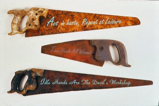 Old Saws , 1990: saws, applied text, paint. Dimensions variable.
Old saws is an expression meaning old proverbs or maxims (which sometimes offer contradictory advice). Each saw is decorated with two such sayings, one on either side. “Act in haste, repent at leisure” reverses to “A stitch in time saves nine;” “Idle hands are the Devil’s workshop” reverses to “All work and no play makes Jack a dull boy.” 