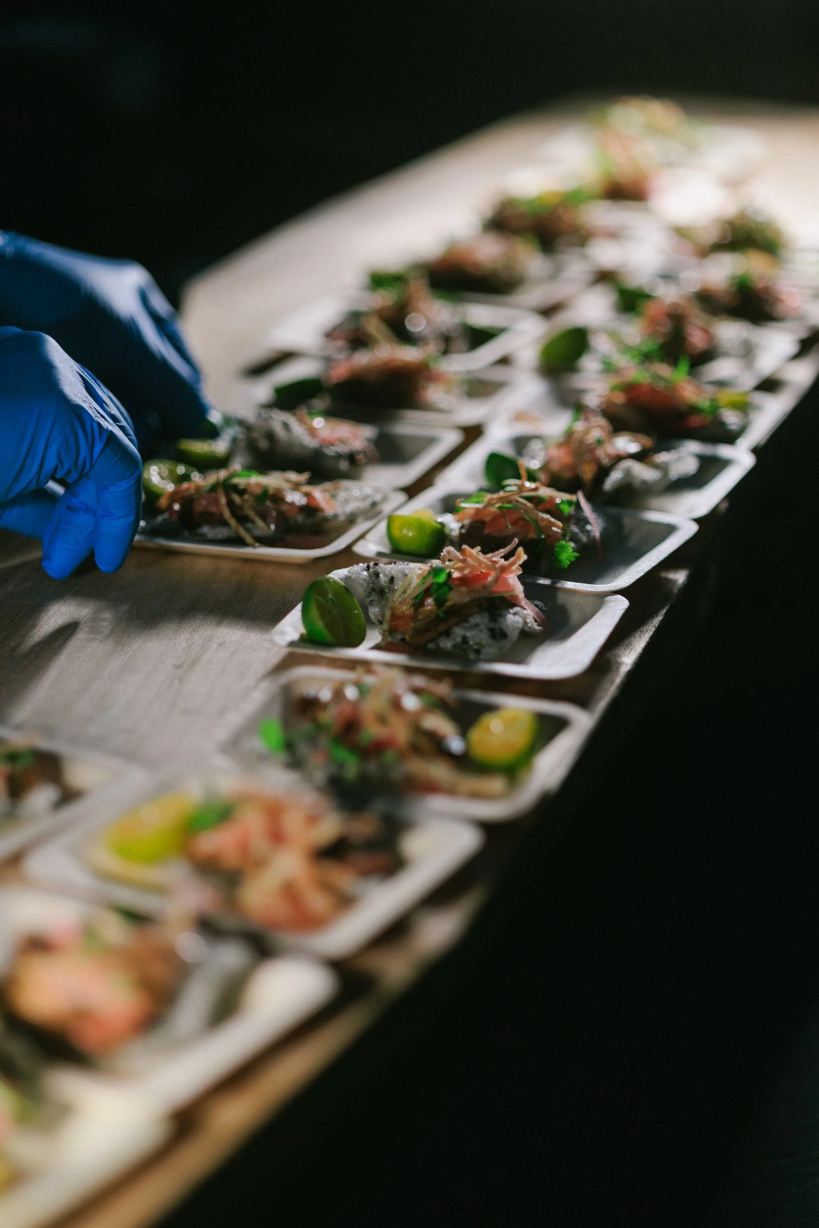 Chef and staff preparing or plating small appetizers with lime garnishes on individual white plates.