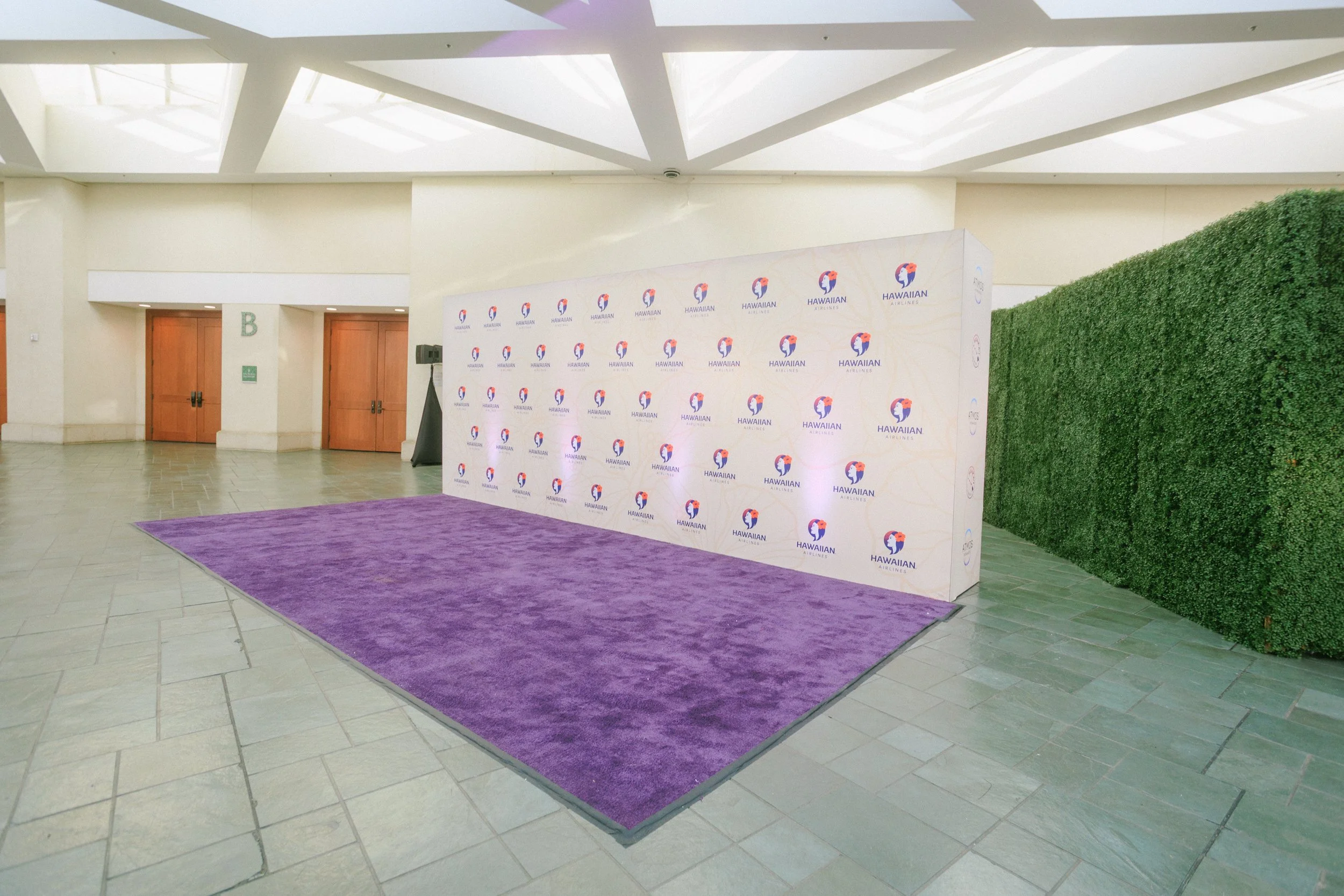 Event backdrop on a purple carpet at Hawaiian Airlines conference or event.