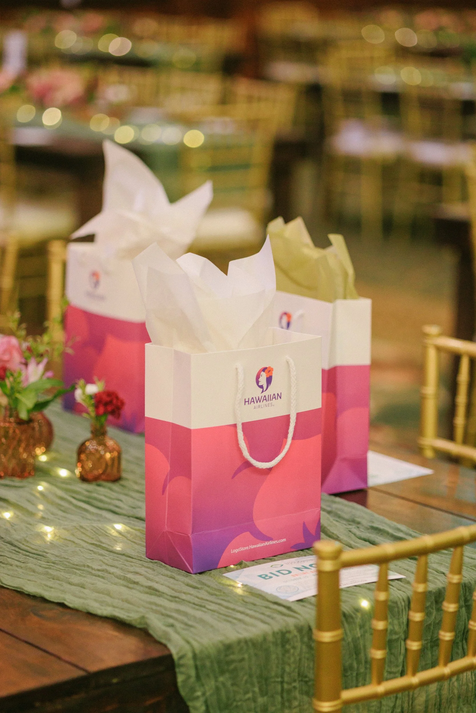Hawaiian Airlines gift bags with tissue paper on a decorated table at an event.