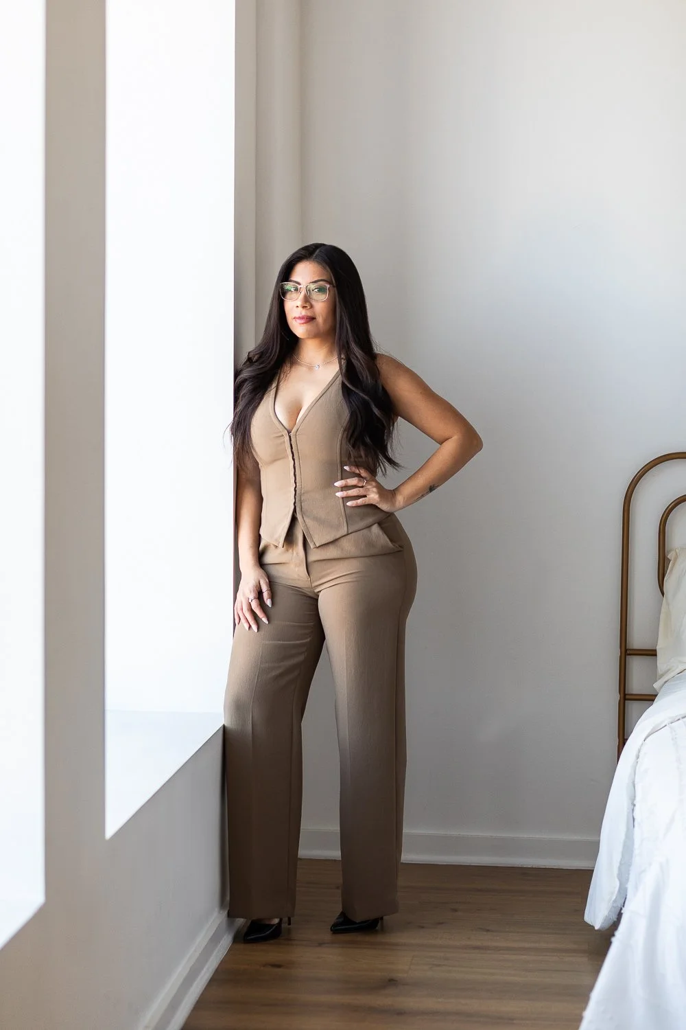 A Chicago realtor stands in a brown powersuit in a modern white room