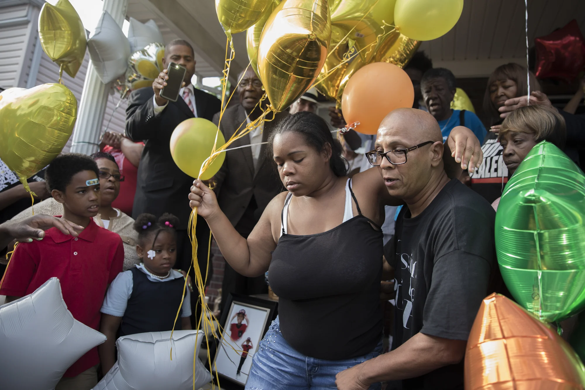 Micheshia Norment, left, holds onto friend Christopher 2X as she prepares to release balloons into the sky in memorial of her son, Dequante Hobbs Jr. He was shot by a stray bullet through their kitchen window in the west end of Louisville, Ky. the night before. He was 7.