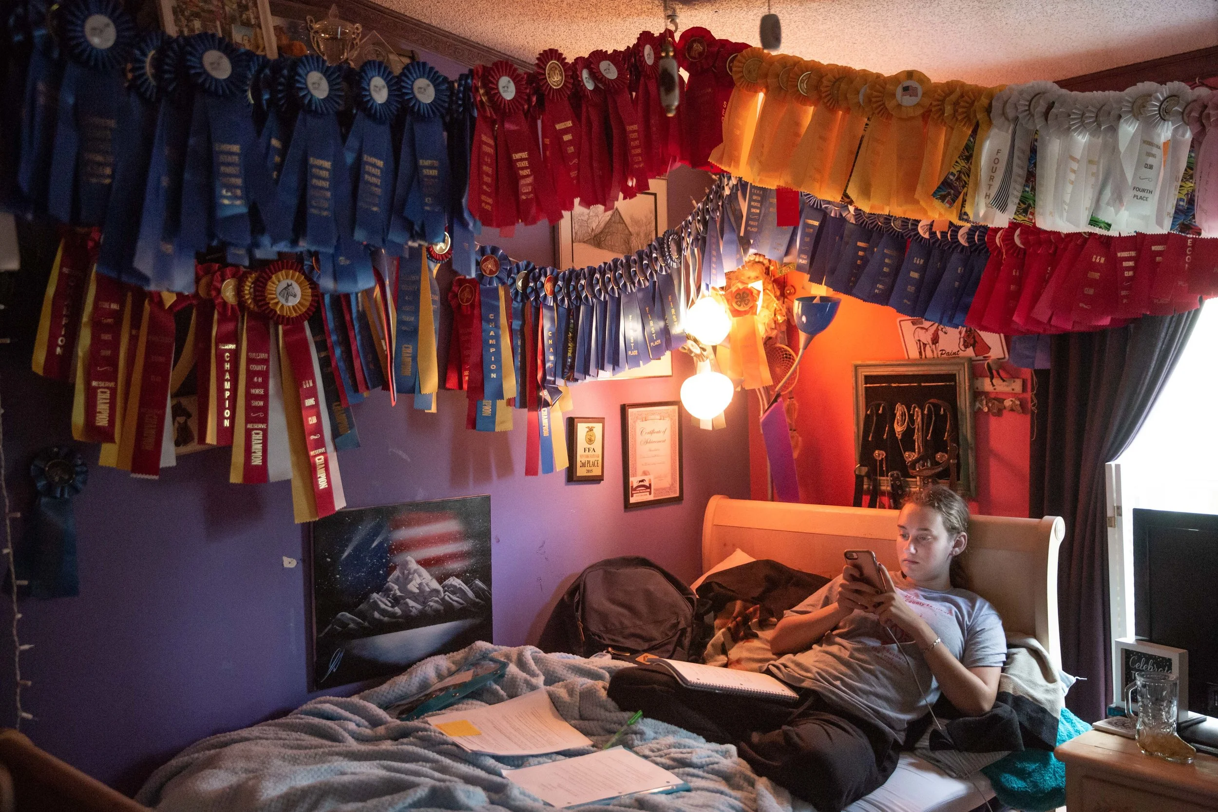  Victoria Epstien, 17, of Liberty, N.Y., takes a break from homework while recovering from Crypto that she got while tending a sick calf. She sits underneath a canopy of horse racing prizes and hopes to join a collegiate equestrian team in college. 