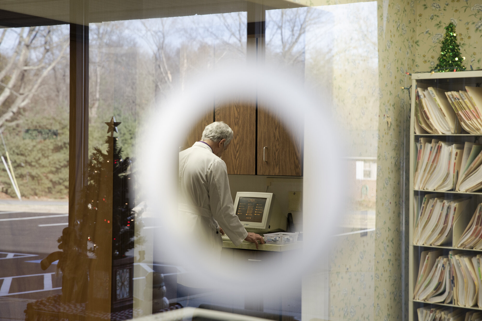 Dr. Moughon reviews patient data on an outdated computer without internet capability.