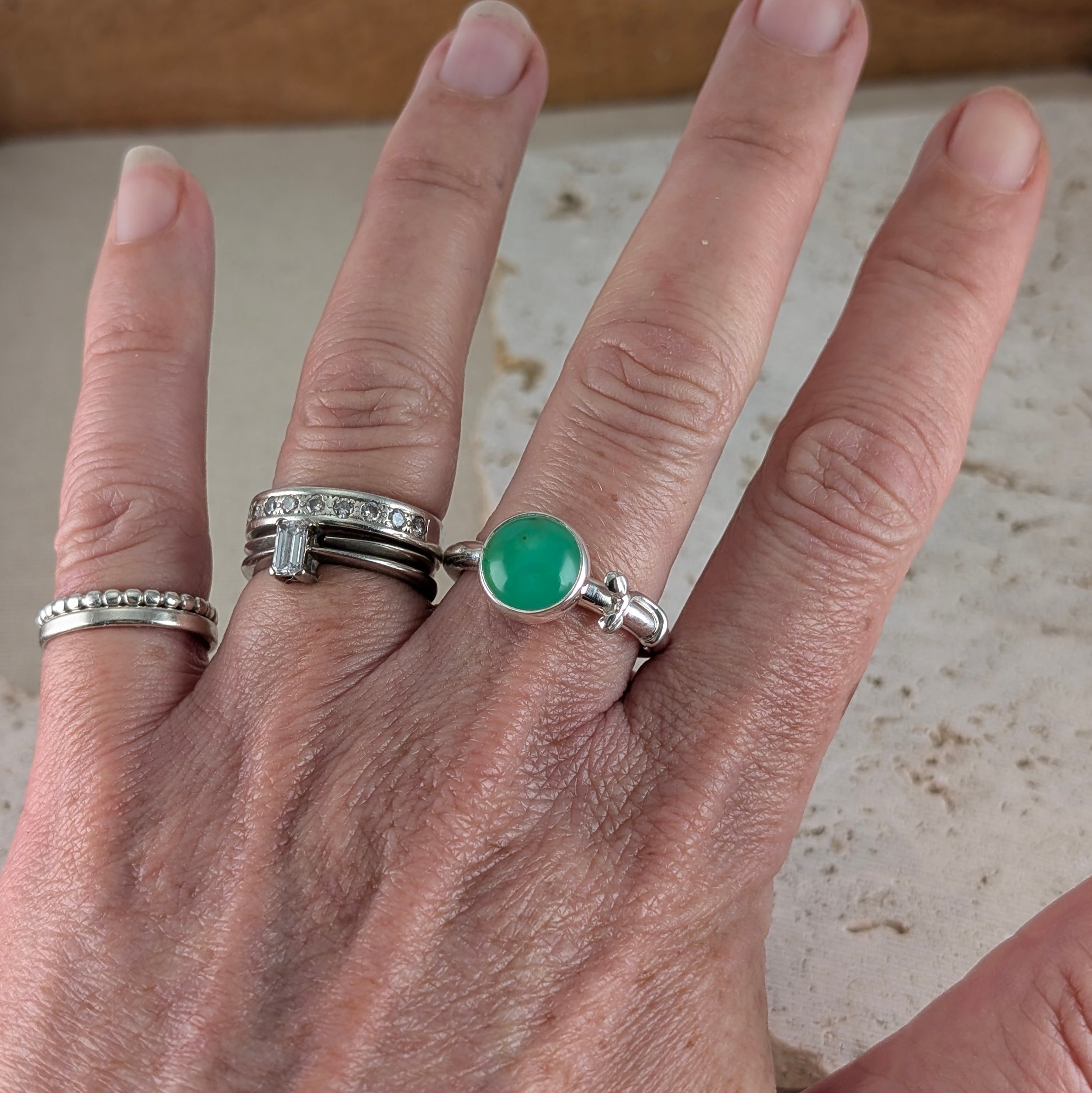 Handcrafted silver ring with a round green chrysoprase gemstone and delicate botanical leaf details wrapping onto the band shown worn on the hand