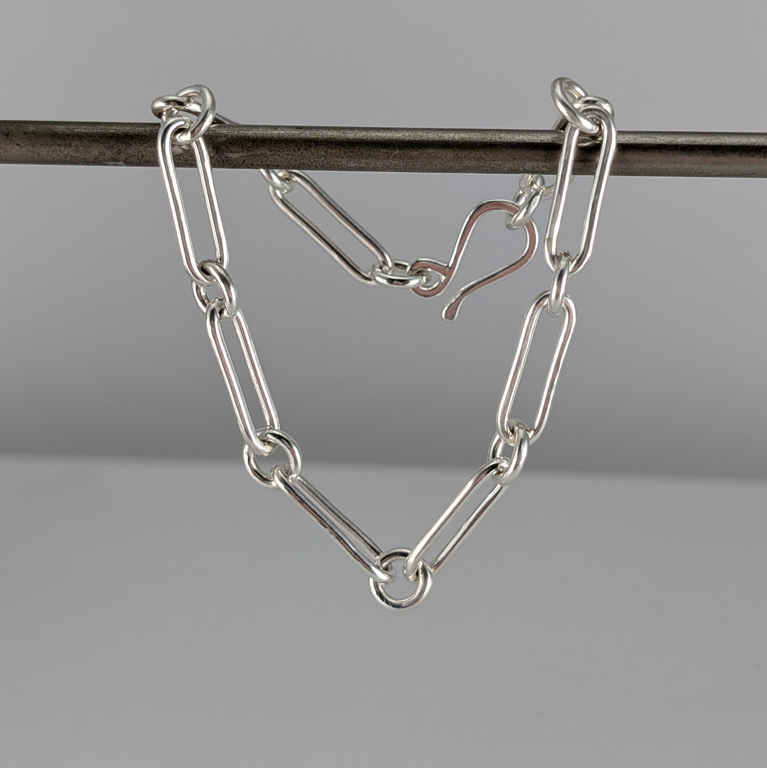 Close-up of a matte Argentium sterling silver figaro bracelet with elongated paperclip links and an S-shaped catch by Georgina Dunn Jewellery.