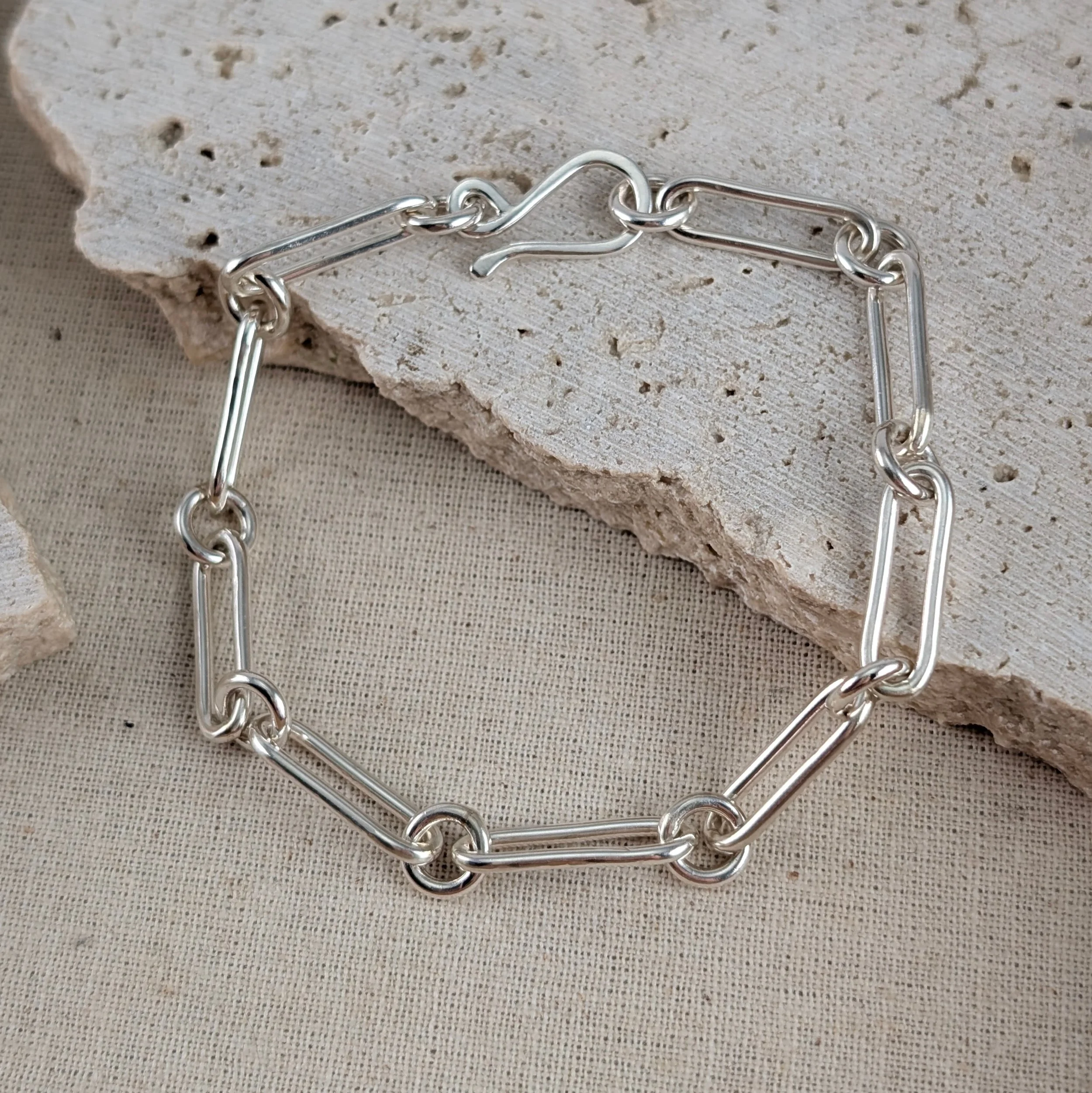 Close-up of a matte Argentium sterling silver figaro bracelet with elongated paperclip links and an S-shaped catch by Georgina Dunn Jewellery.