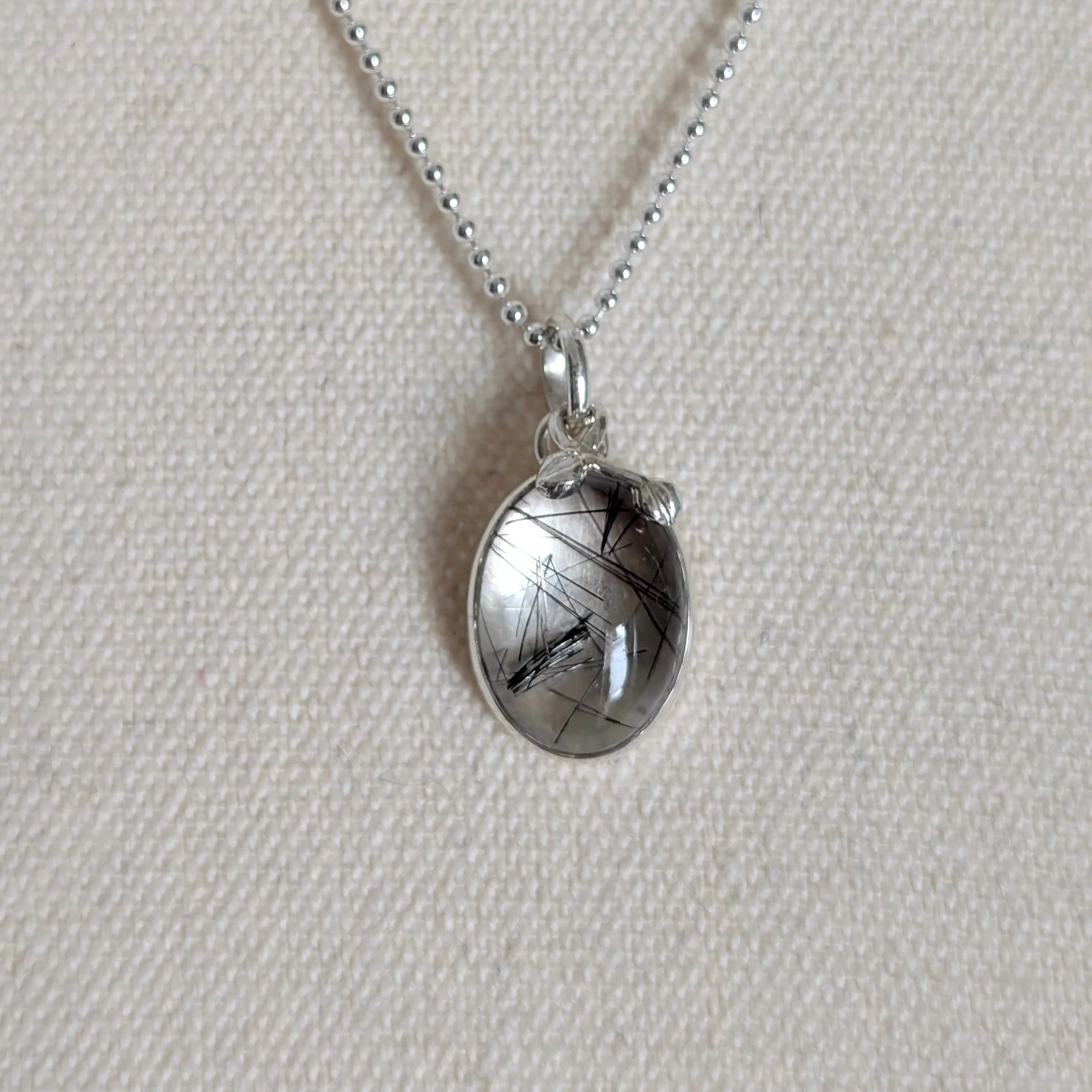 Rutile Quartz Pendant with Leaves on Ball Chain Necklace shown hanging on a calico mannequin