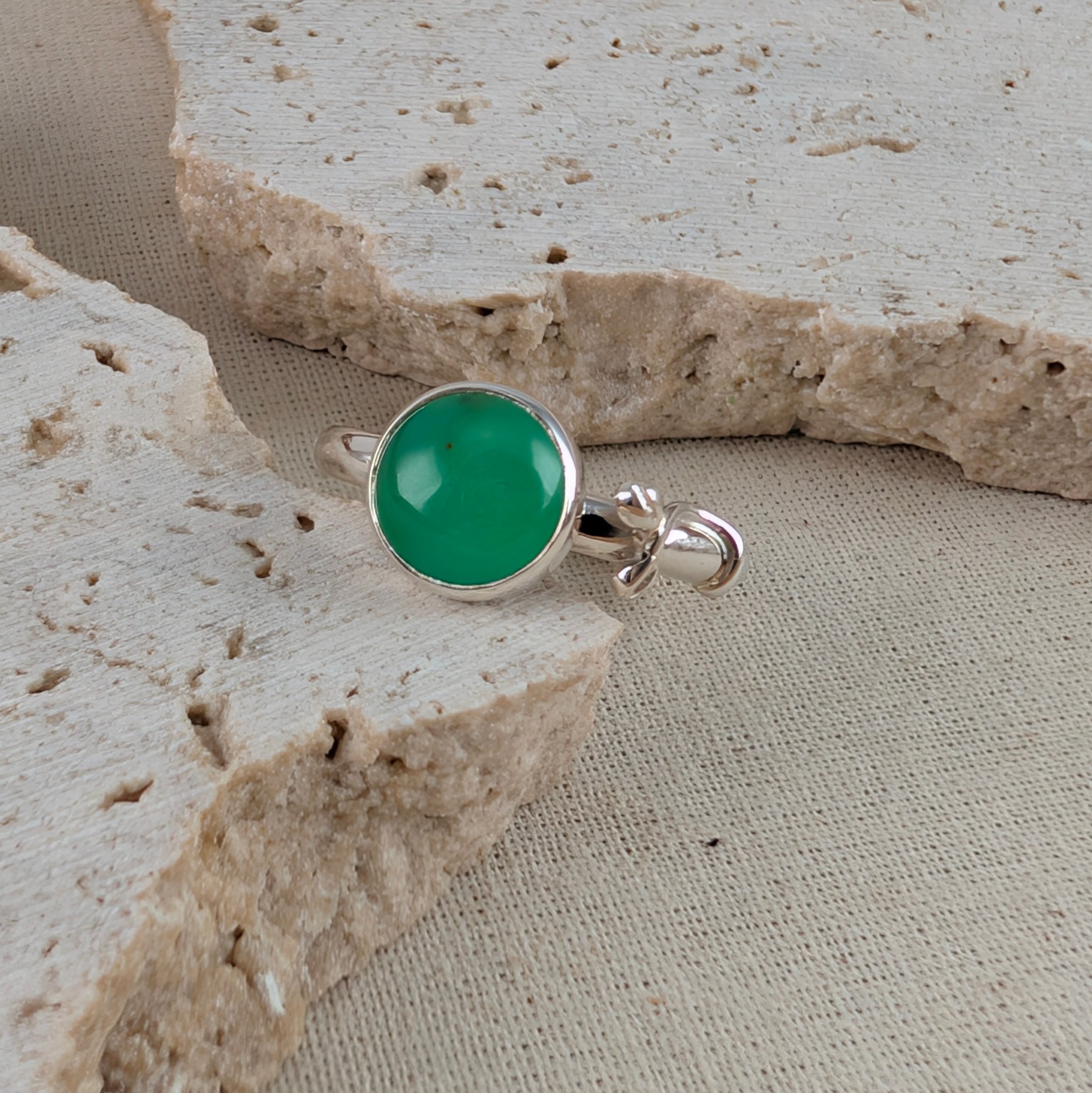 Handcrafted silver ring with a round green chrysoprase gemstone and delicate botanical leaf details wrapping onto the band