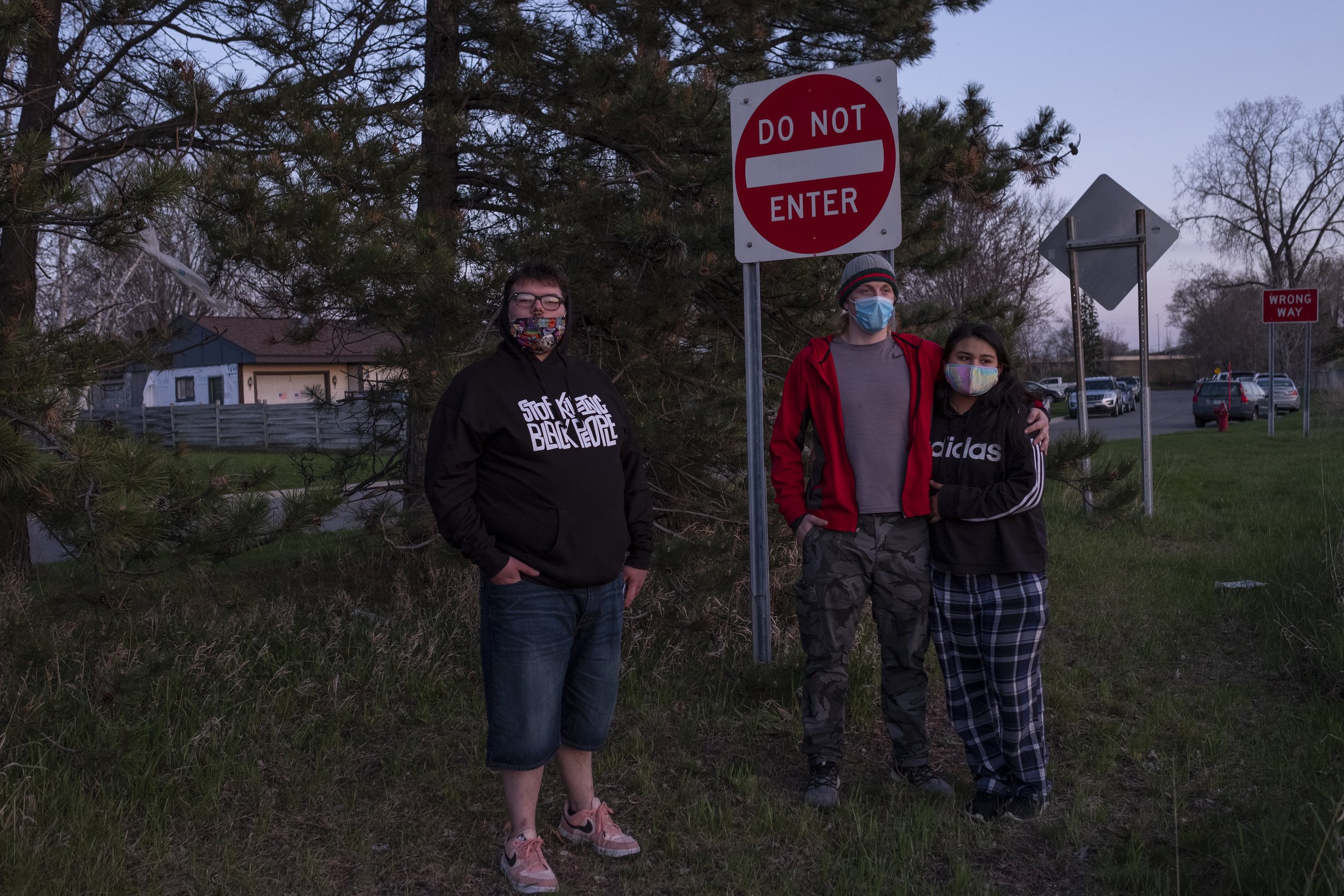  Zachary Henry (left) and Maximillian Fauble (center) stand with another person, who did not want to be identified, and watch along with a march in Brooklyn Center near the police department on Friday, April 16th. For the sixth consecutive night, pro