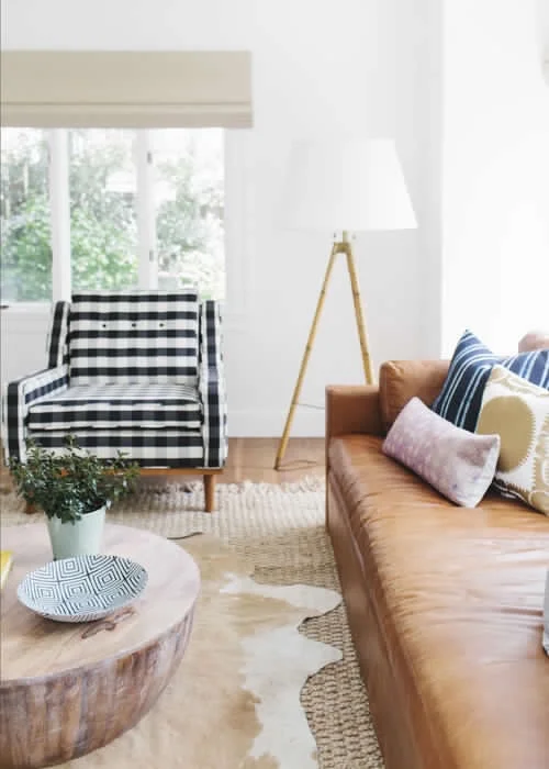 Layered rugs add awesome texture to a bright and airy living room by Studio McGee. And we love us some buffalo check on that chair!