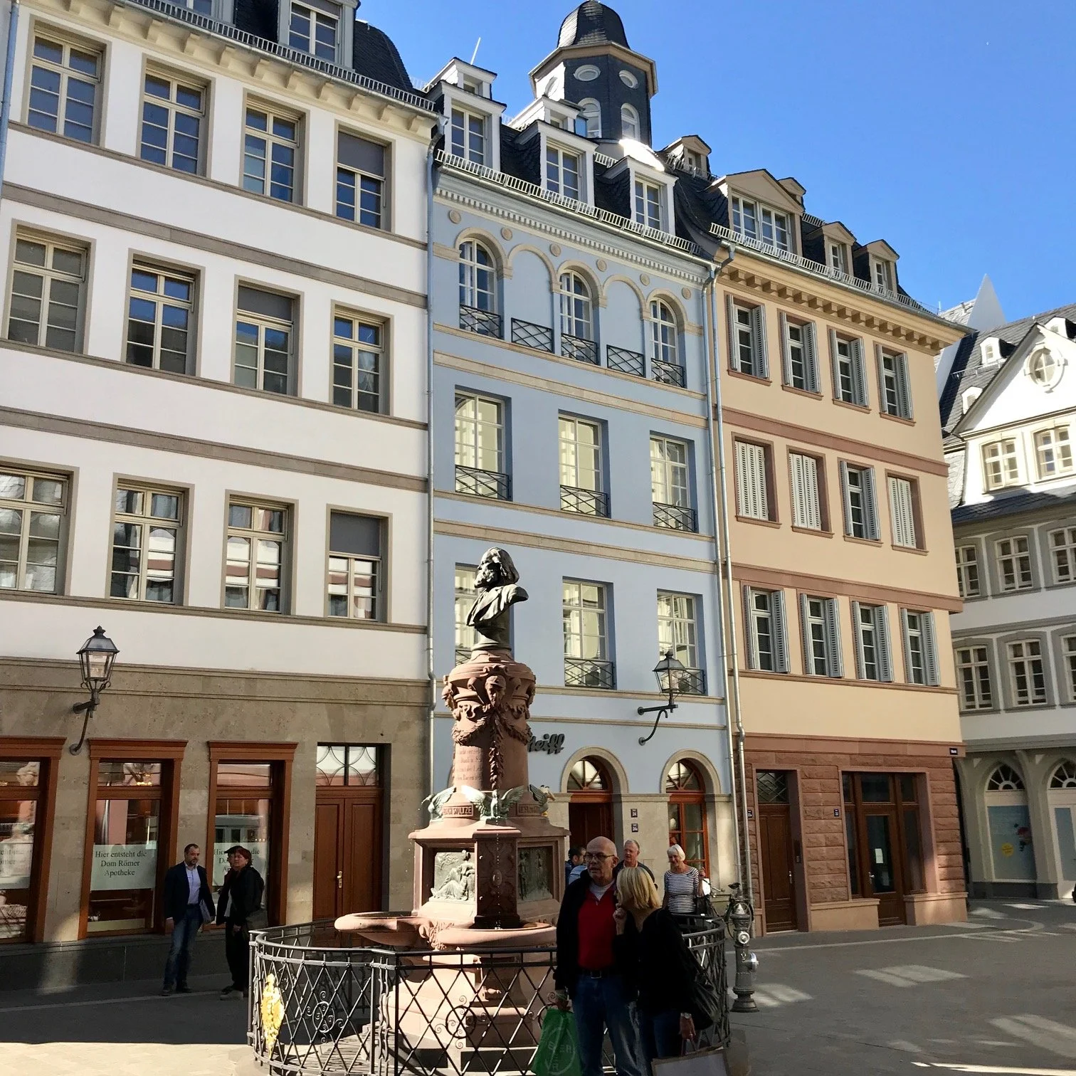 Classicist buildings on the Hühnermarkt, Frankfurt. Colorful historic buildings with large windows and a small fountain with a bust of Friedrich Stoltze.