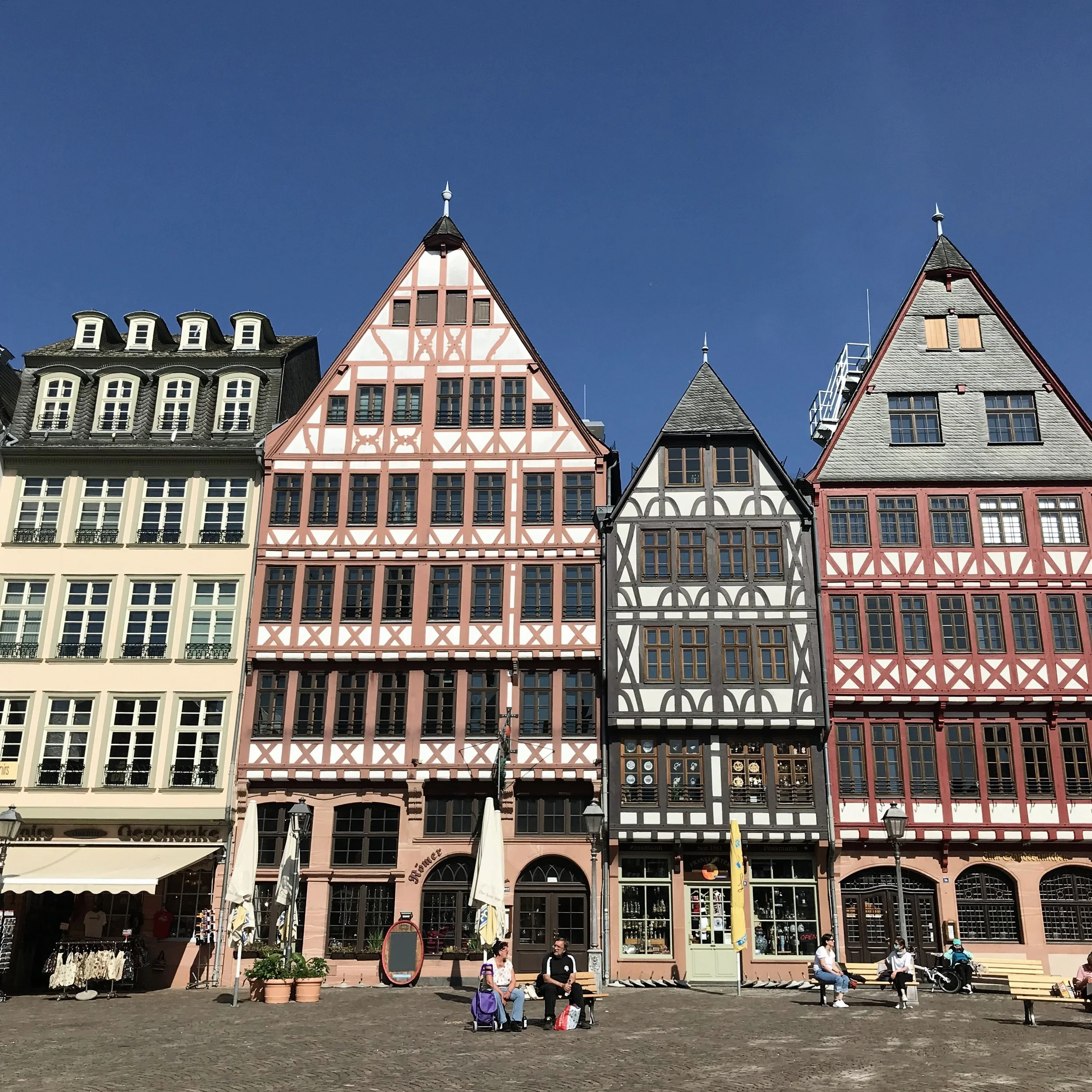 Colorful, historic-style buildings on the Römerberg in Frankfurt with cobbles, cafes and outdoor seating.