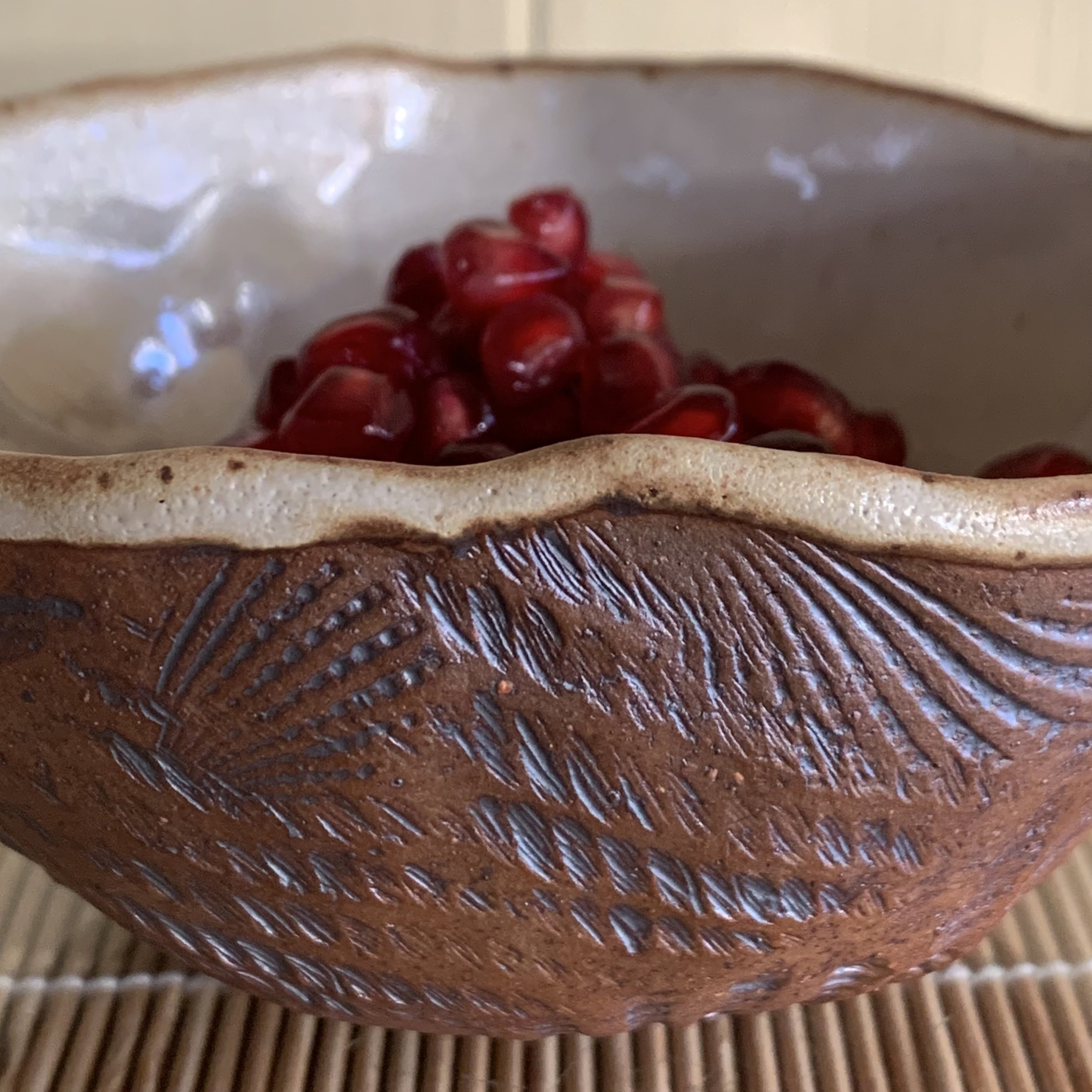 Bisque pieces are dipped in large buckets of glaze and transported to her gas kiln where she usually fires over a hundred pieces at once. The 12-14 hour firing cycle is monitored every half hour to produce the reduction atmosphere color richness she