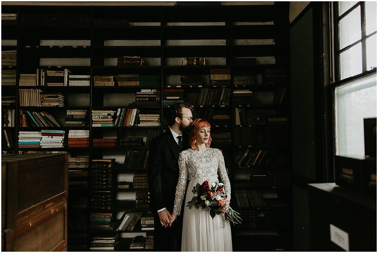  bride and groom portrait in front of books 
