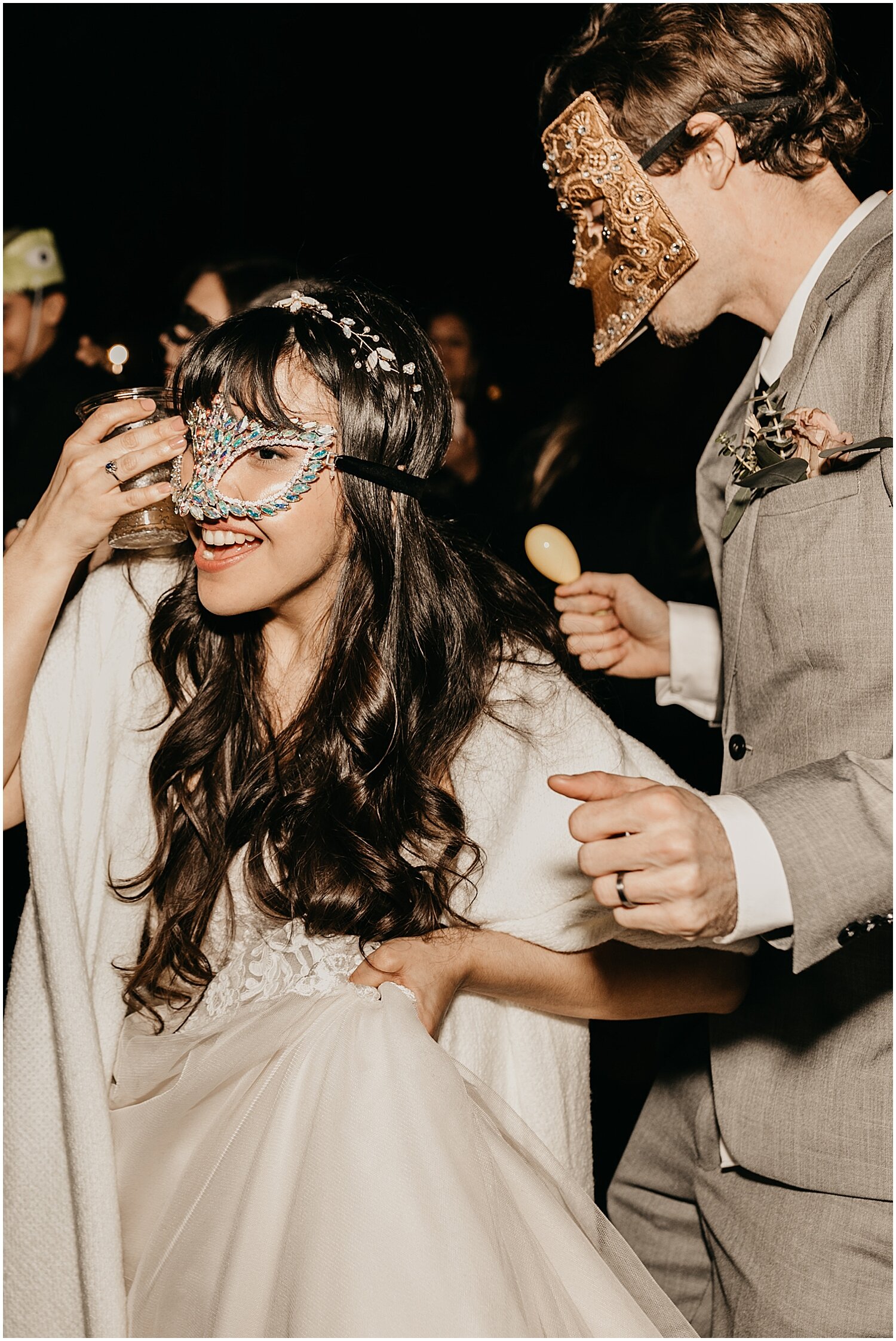  bride and groom wearing mascarade masks during wedding reception 