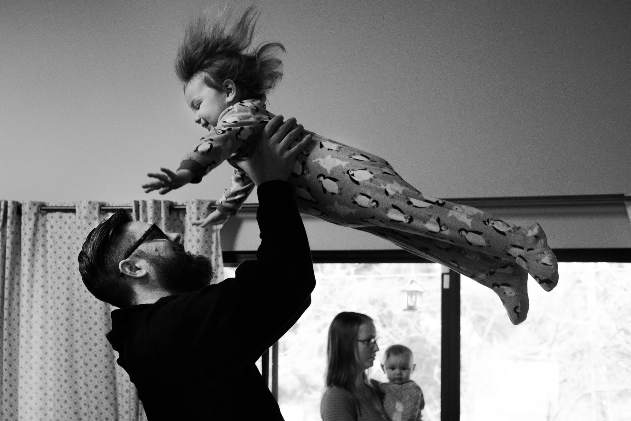 Dad dancing with toddler in pajamas in the air