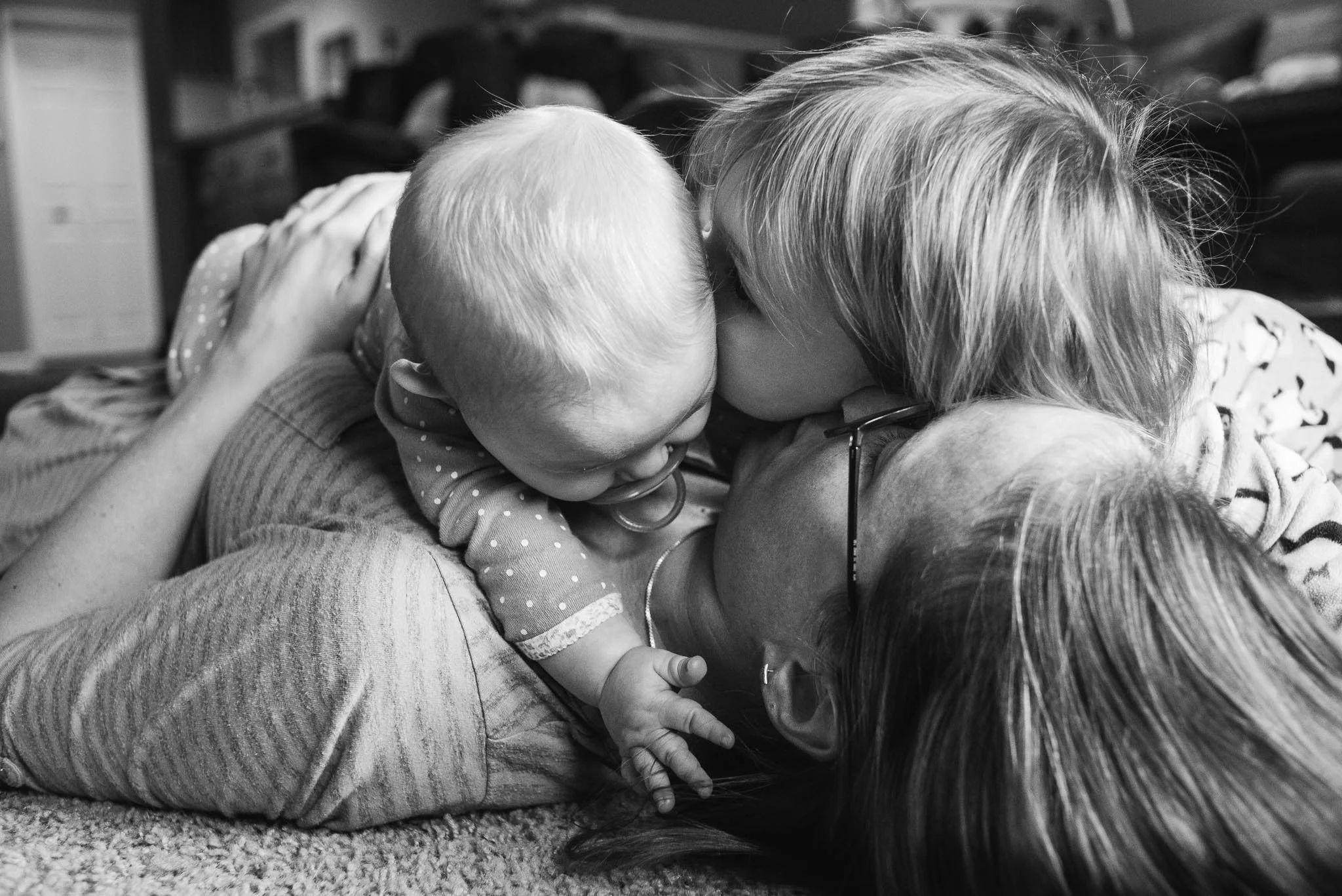 Mom on floor kissing 2 of her daughters