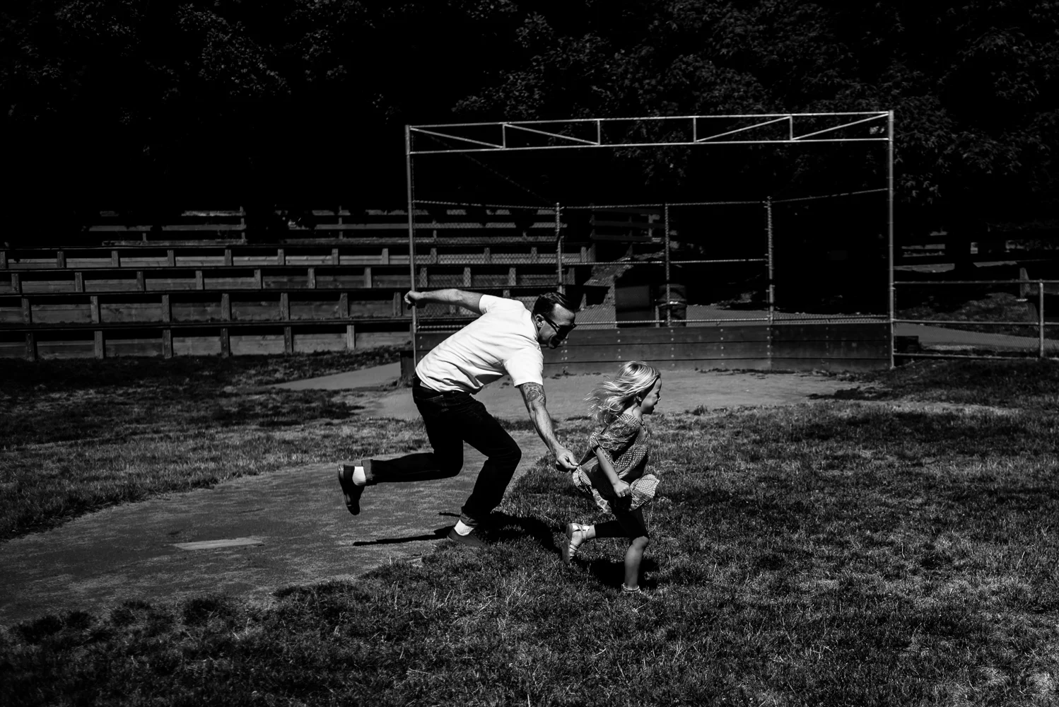 Dad playing tag with 5 year old daughter on baseball field