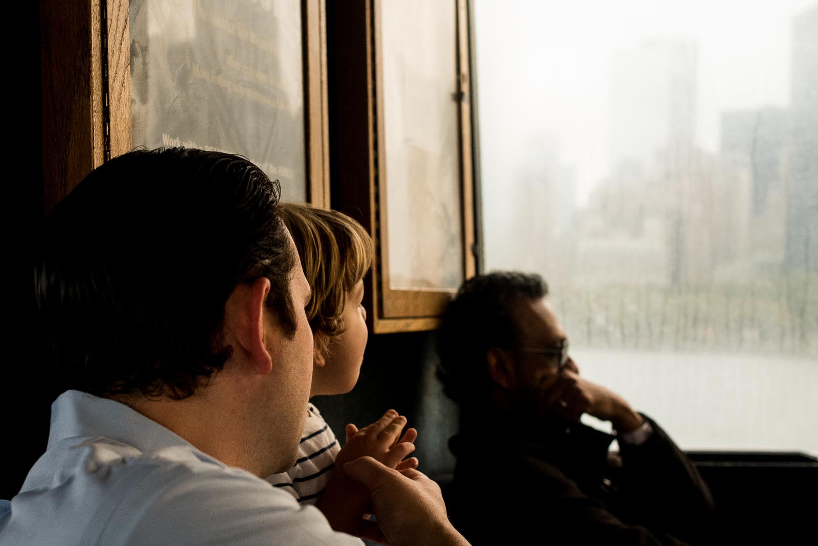 Father and son looking out ferry window at NYC skyline