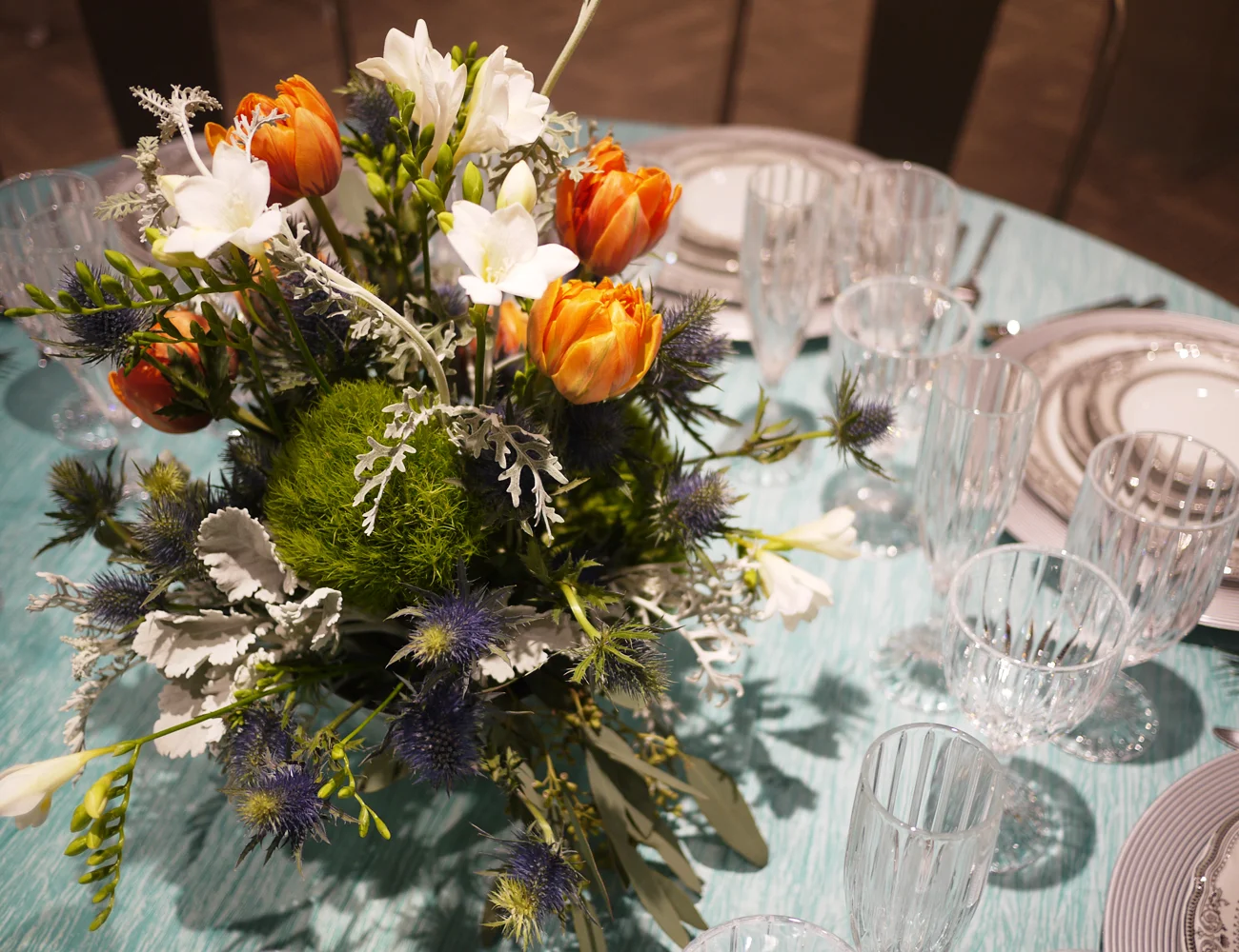 We used a beautiful vintage silver compote for this arrangement of tulips, freesia, dianthus, sea holly, eucalyptus, and dusty miller. A very unique combination to complement the table setting from Alpine Party Rentals.