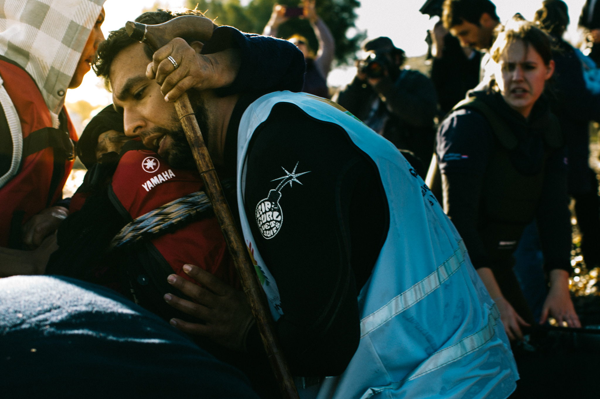 Clutching a cane, an elderly woman is helped off the boat by one of the dozens of volunteers waiting on the shores of Lesvos for incoming rafts.