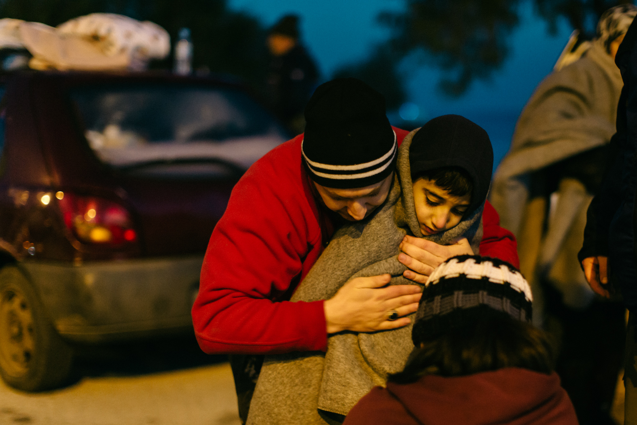 On this early winter morning in January, a volunteer wraps a young boy in an effort to fight off hypothermia. Spray kicked up by the strong gusts on the Aegean soaked people in every boat that made landfall that morning.