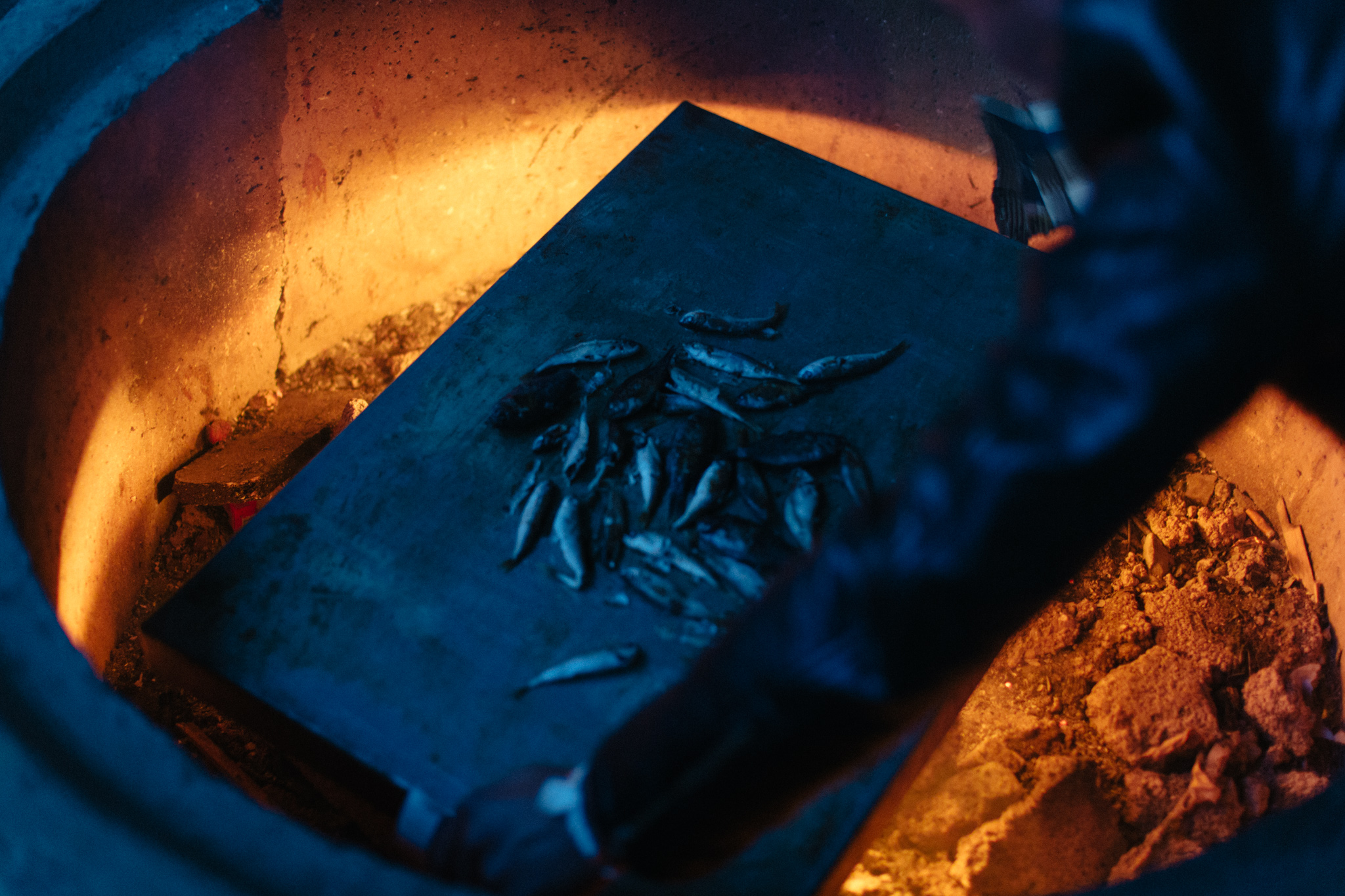 Afghan men cook bite-sized fish they caught in the nearby harbor of the small island of Leros, Greece.